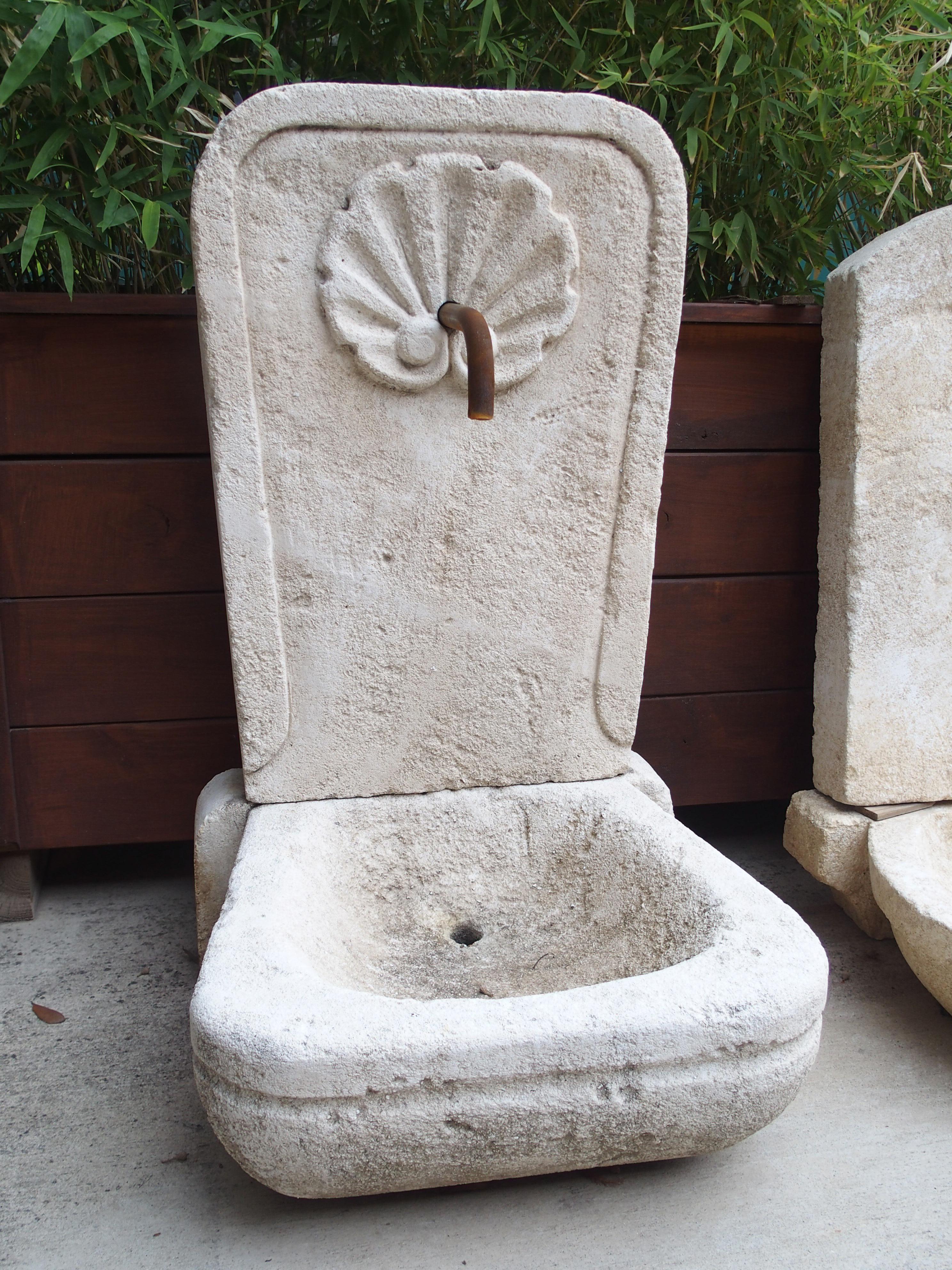 From Provence, France, this small wall fountain features two pieces of hand carved Estaillade limestone. The cream colored stone has developed a lovely golden brown patina in some areas, giving it a lovely, variegated appearance. A large, scalloped