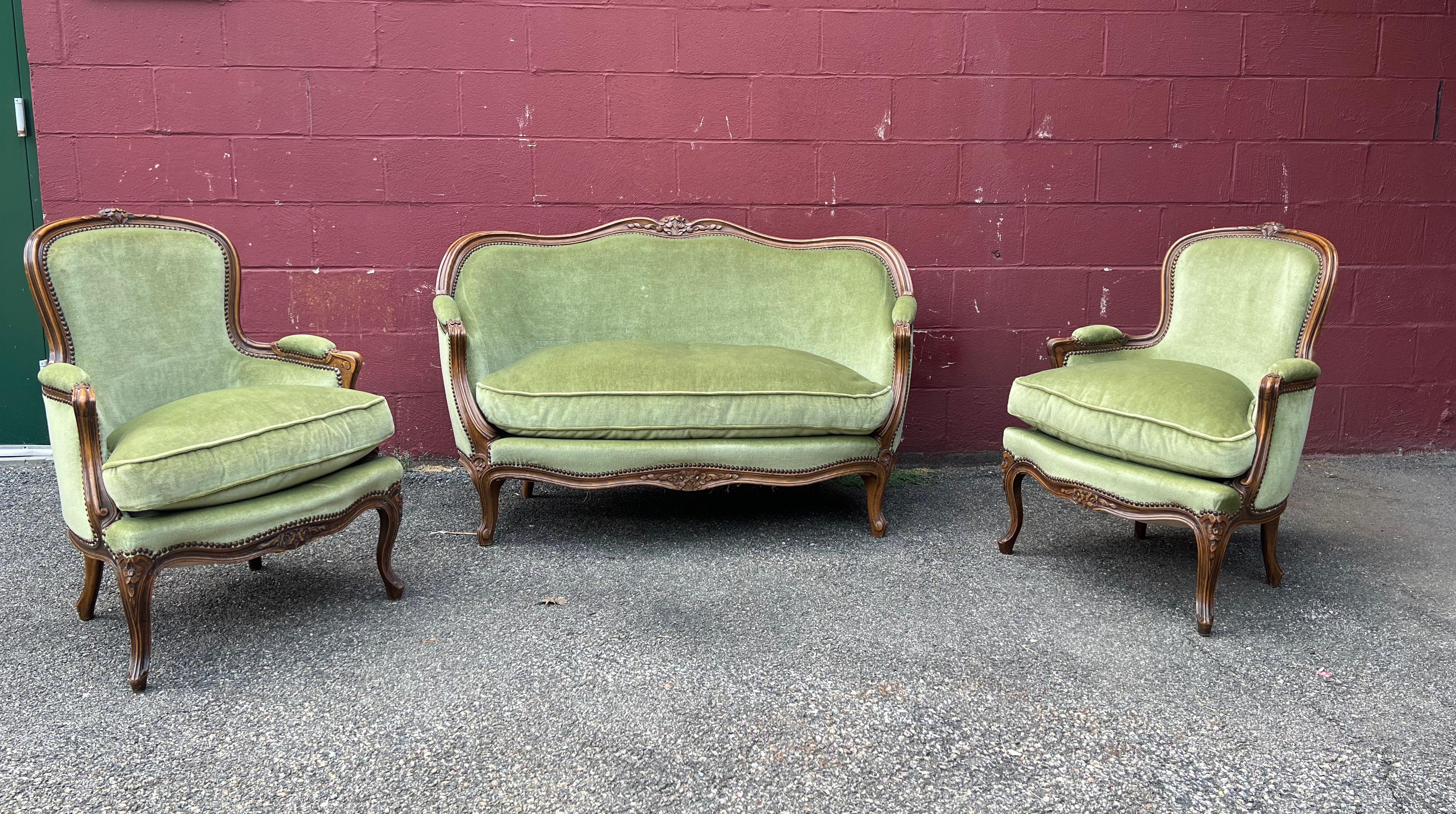 A classic French Louis XV style settee upholstered in a rich medium green velvet. The fruitwood frame has hand carved floral motifs and graceful curved legs. Very good vintage condition. This sofa is part of a set that has a pair of matching