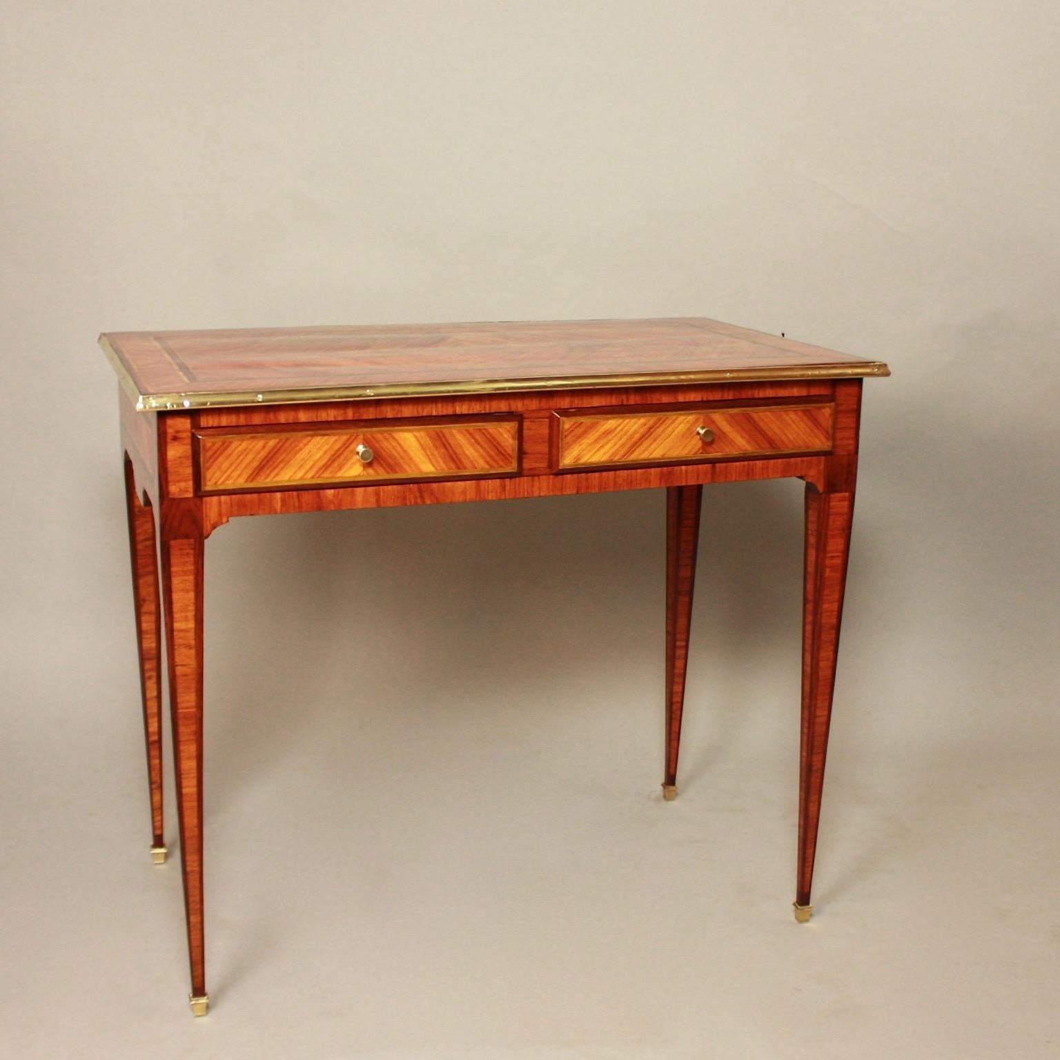 A small bureau plat or writing desk, the rectangular gilt-bronze banded top quarter veneered in kingwood. The panelled frieze compartment with two frieze drawers, each with a dummy drawer at the back. With leather lined candle slides, on panelled