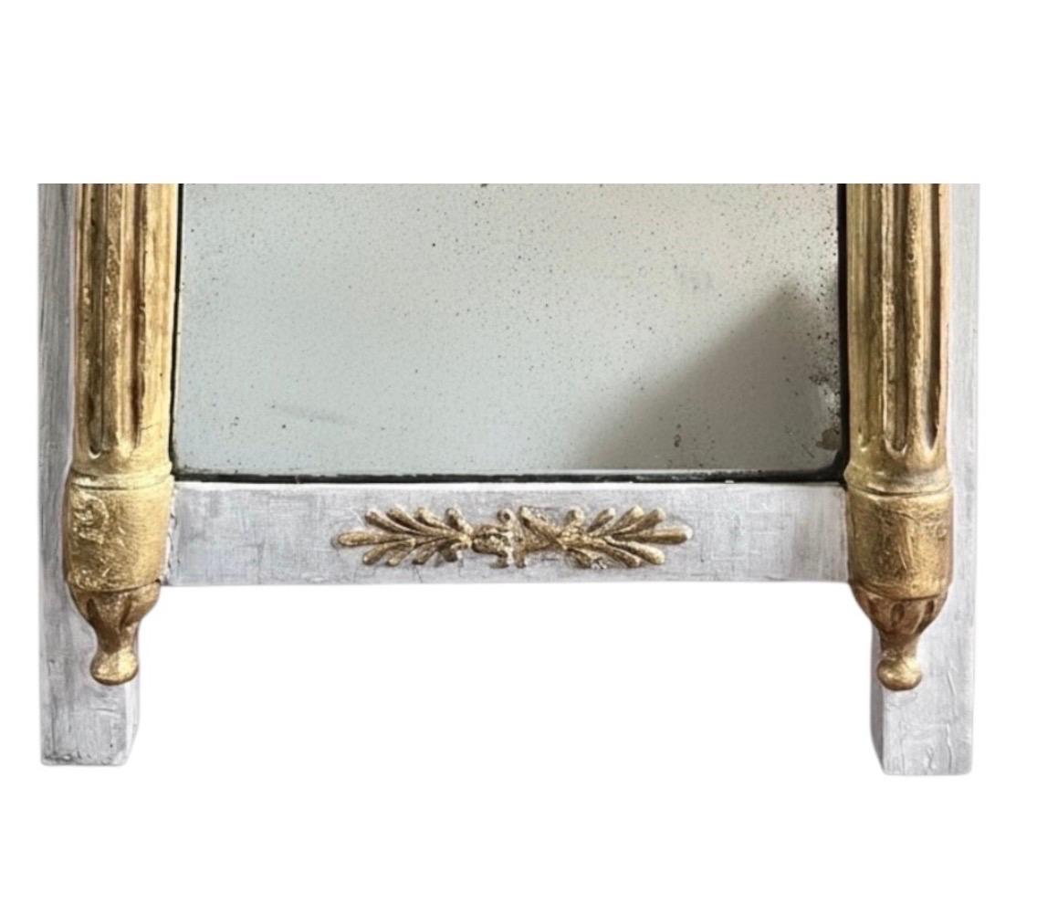 Charming small Louis XVI / Directoire period mirror, featuring a carved and gray-painted wooden frame, enhanced with gilt highlights highlighting the ornaments.
The frame is punctuated by fluted column uprights, typical of the neoclassical style of