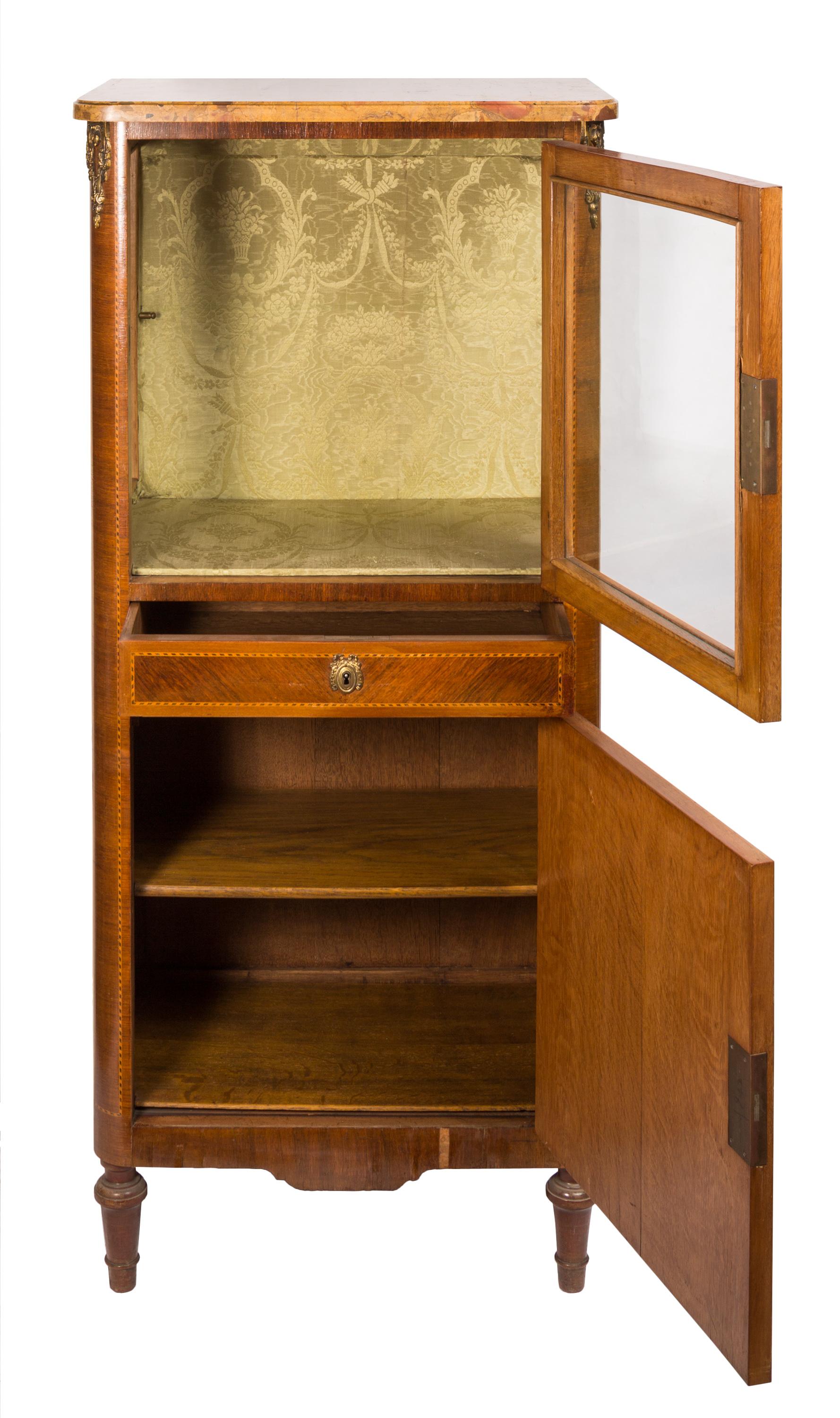 Small size French Louis XVI style display vitrine with marquetry inlay details, decorative fabric interior and marble surface top. The top half of the cabinet features glass sides and locking front door, the lower part a locking drawer and closed
