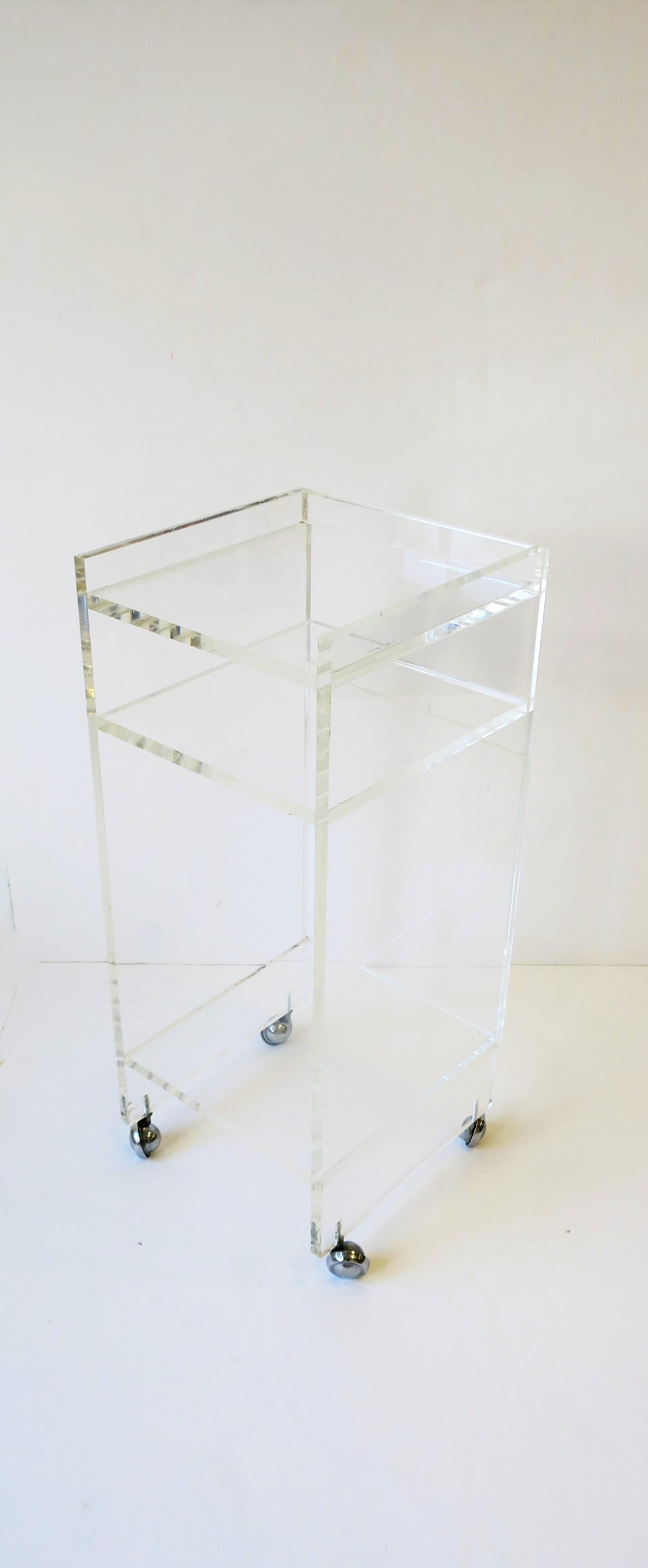 A small, substantial, and convenient Lucite bar cart on caster wheels. Piece can also be used as a storage piece, bookcase, or cabinet. It has three storage areas; top shelf, middle shelf, and lower shelf. This is a great piece, especially if space