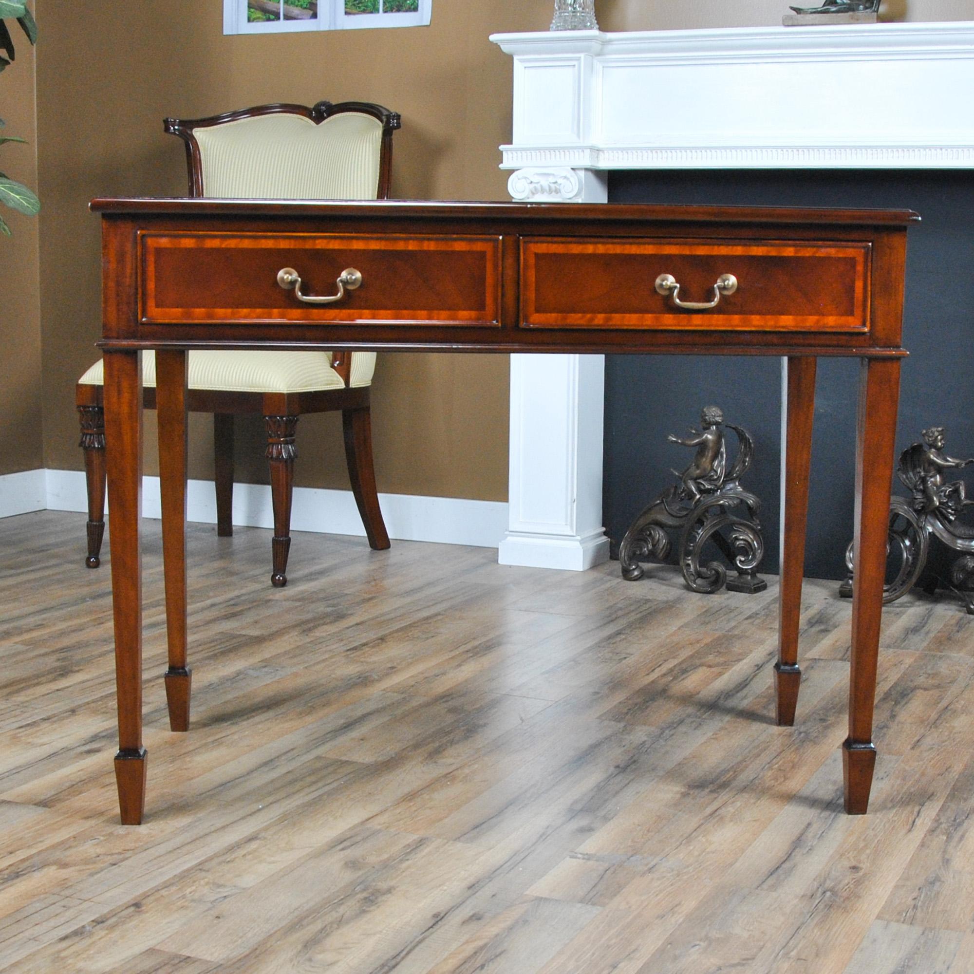 A high quality Small Mahogany Banded Desk from Niagara Furniture made of mahogany and satinwood with solid brass drawer pulls. The two dovetailed drawers denote high quality construction and the elegant tapered legs end in a popular spade foot