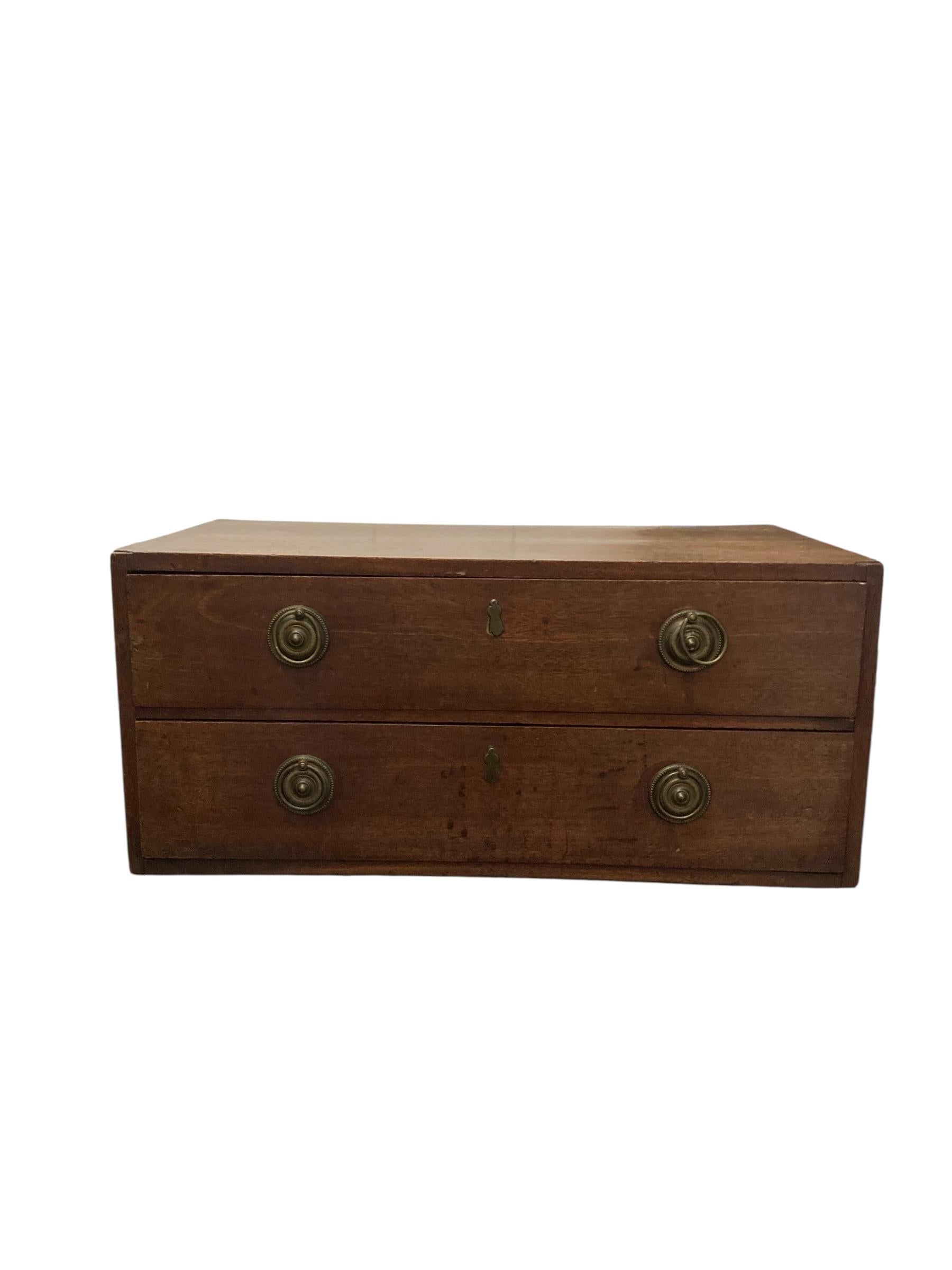 Small Mahogany Campaign style chest of two drawers CIRCA Late 1800's. Featuring exquisite brass handles that add a touch of sophistication. Perfect for compact spaces, this versatile piece offers ample storage while enhancing the aesthetic of any