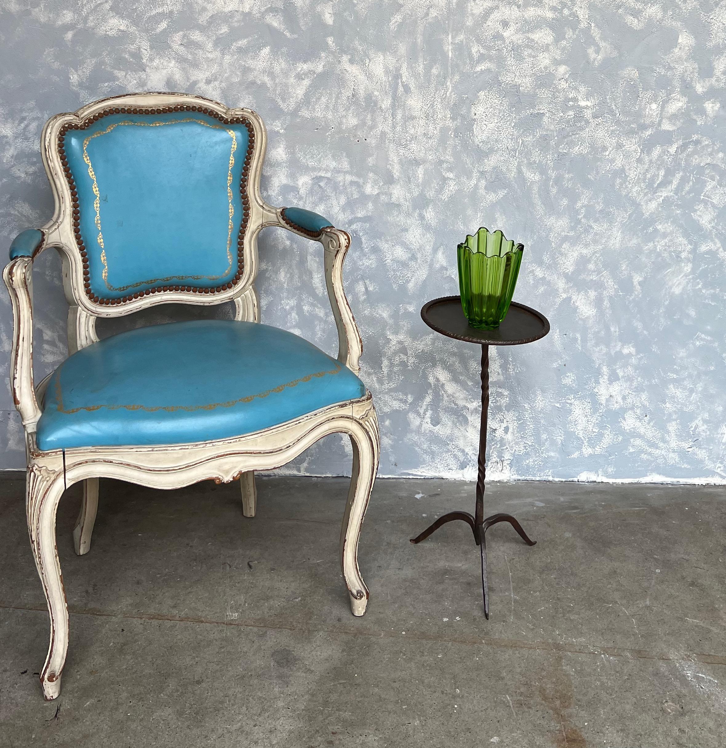 This unique small side table from 1950s Spain stands out with its round top enclosed in a rolled rim, mounted on an ornamental twisted stem. The table, made of patinated iron, rests on a delicate tripod base with tapered and pointed feet, adding to