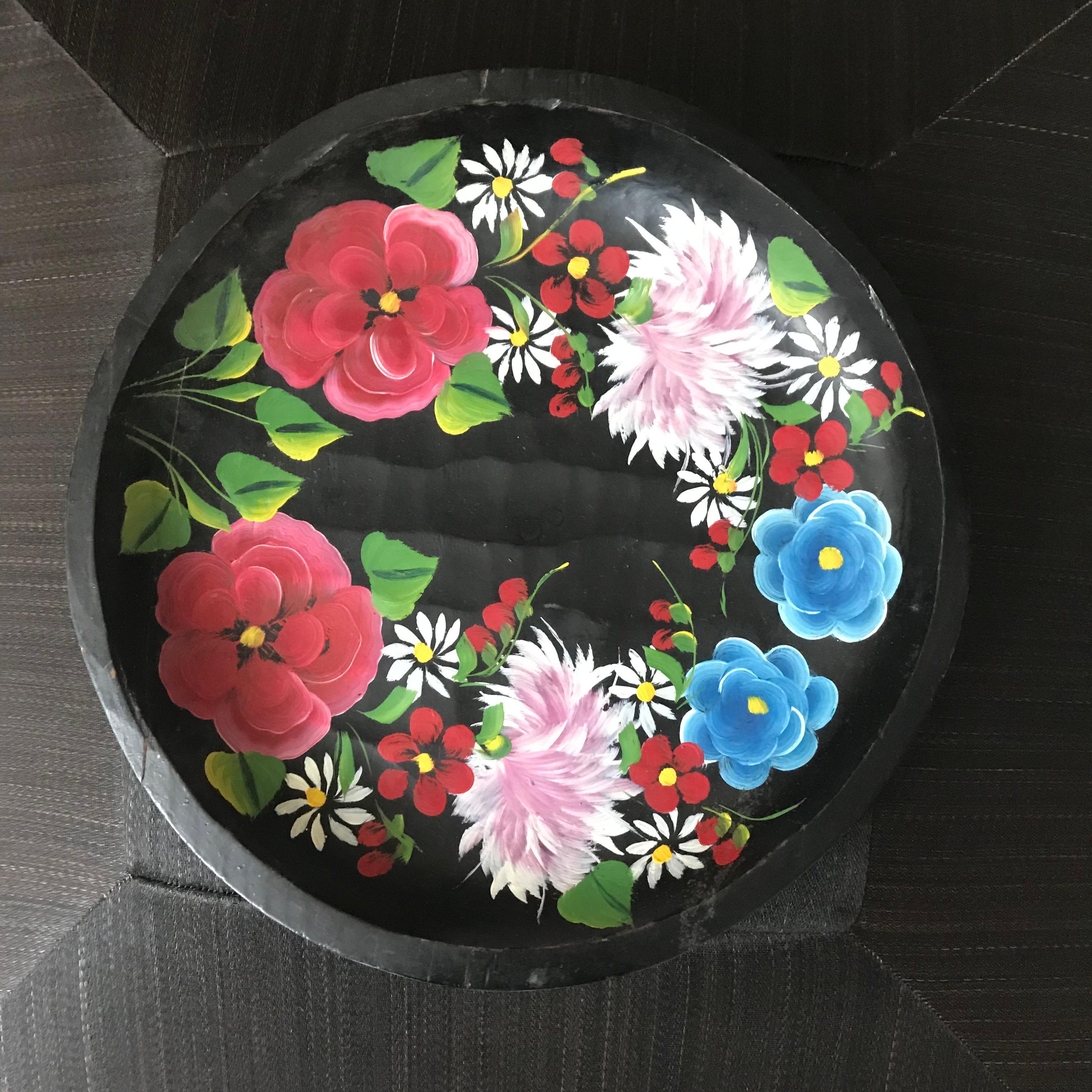 A beautifully crafted Mexican wooden plate featuring a black base and vibrant hand-painted flowers. This piece combines traditional craftsmanship with colorful artistry, perfect for adding a cultural touch to any space.