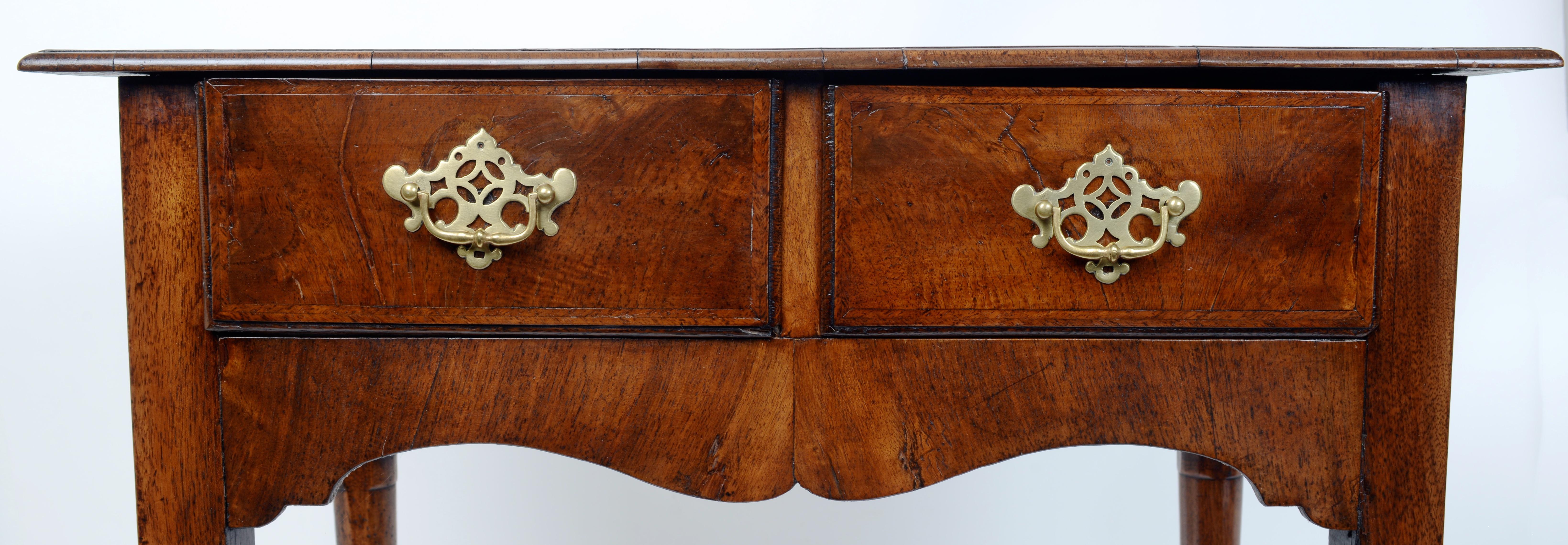 A Small Mid 18th C Walnut Lowboy Raised on Turned and Tapered Cabriole Legs Ending on Pad Feet. The lowboy has great proportions. The top with cross-banded bookmatched veneers above two veneered oak lined drawers over the shaped apron. The lowboy