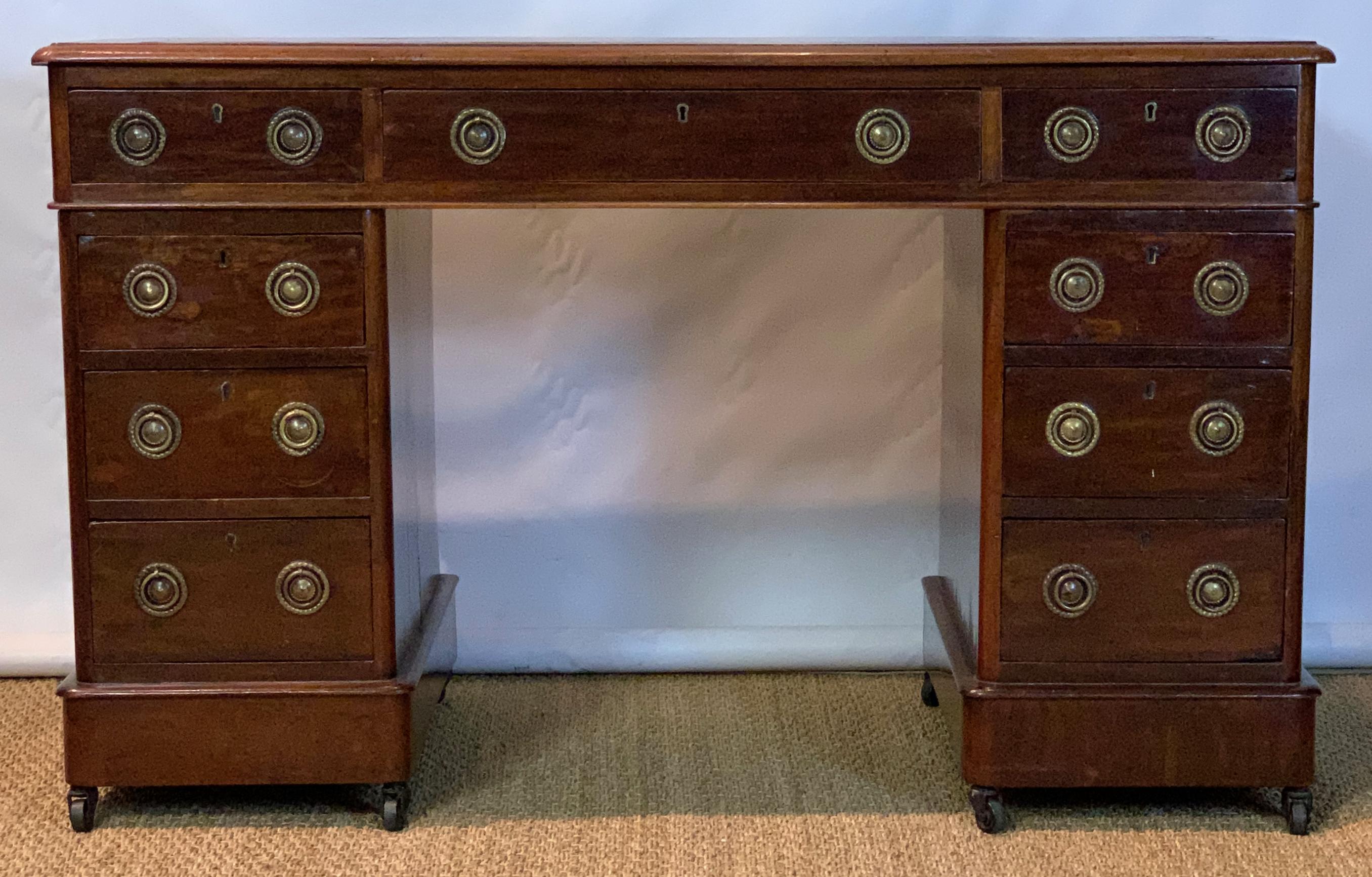 A mid-19th century mahogany pedestal desk inset with original red tooled leather top above 2 short and one long drawer and three drawers in each pedestal.