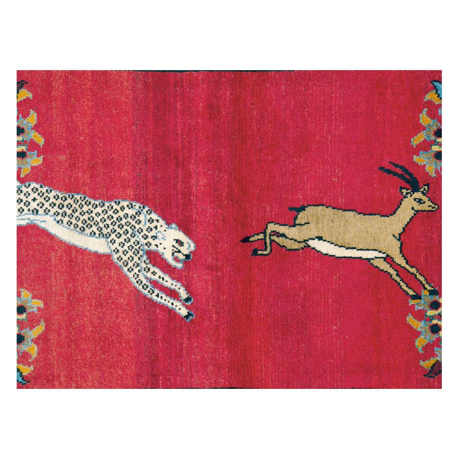 A vintage Persian Tabriz small accent rug handmade during the mid-20th century with a pictorial design of a leopard chasing a deer over a red background. Colorful birds and floral elements over a cream field create the border.

Measures: 4'3
