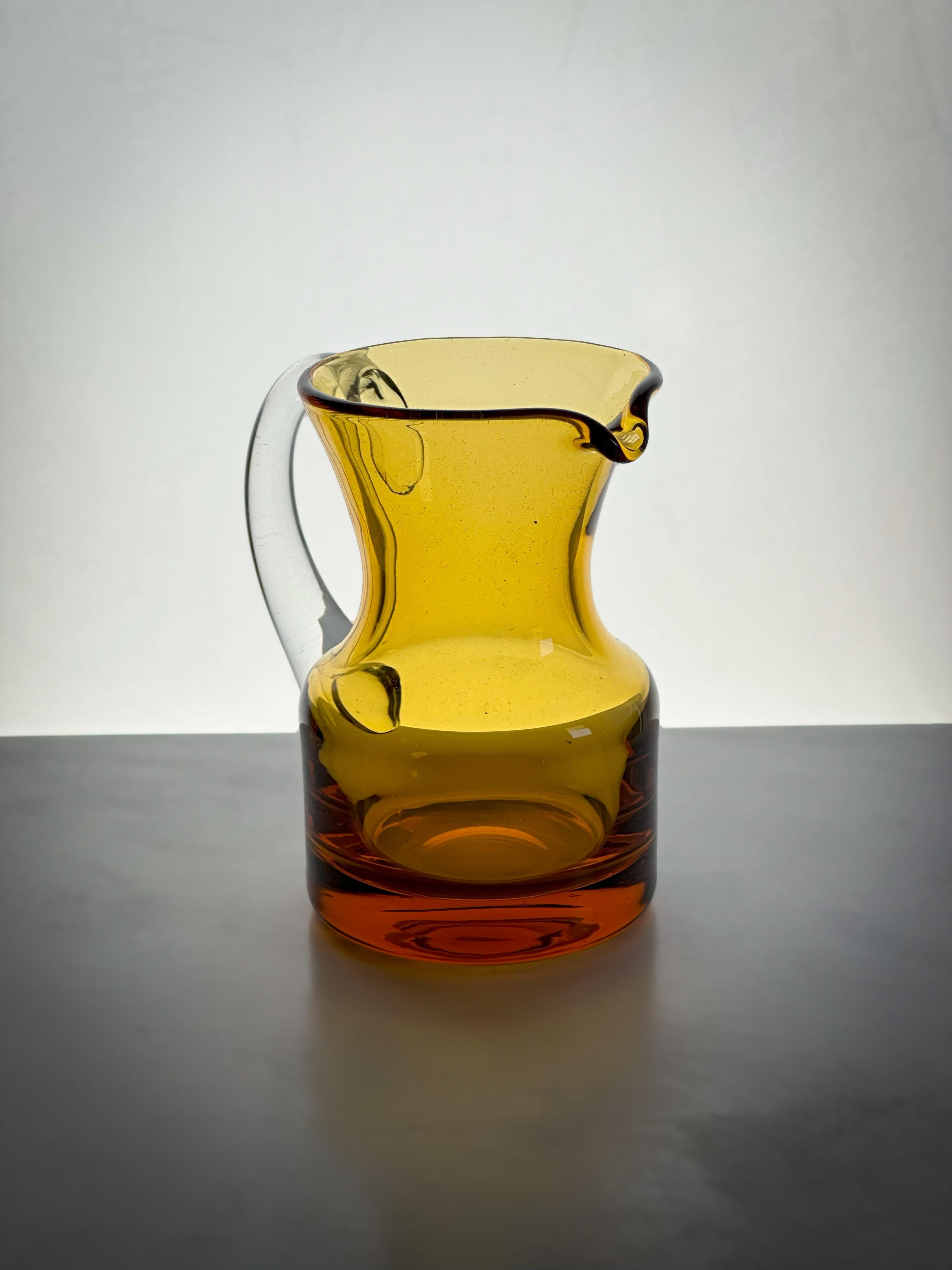A small amber-glass jug, crafted in the 1960's by the esteemed English glassmakers Whitefriars. A fine example of mid-century design and craftsmanship.

Originally conceived as a milk jug or creamer, it belongs to a broader collection of server ware