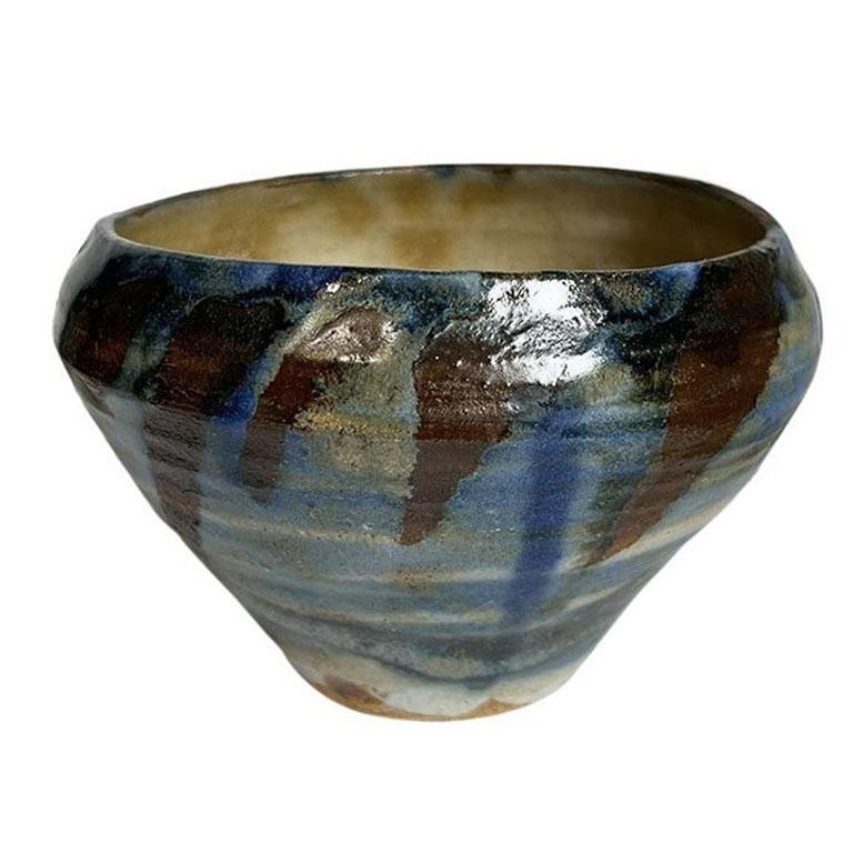 A petite hand-thrown drip ceramic bowl in blue and brown. This piece is small and perfect for use as a trinket dish for change or keys. The vessel is round in form, and features dripped glaze in a range of blue and brown. The bottom is unsigned.