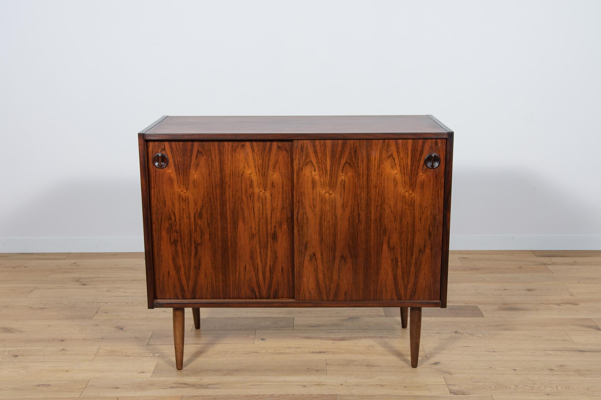 
A small sideboard made of rosewood made in the 1960s in Denmark. Sideboard opened with a two sliding doors.The sideboard has profiled rosewood handles. There are shelves inside the sideboard. The sideboard has been completely renovated. It has been