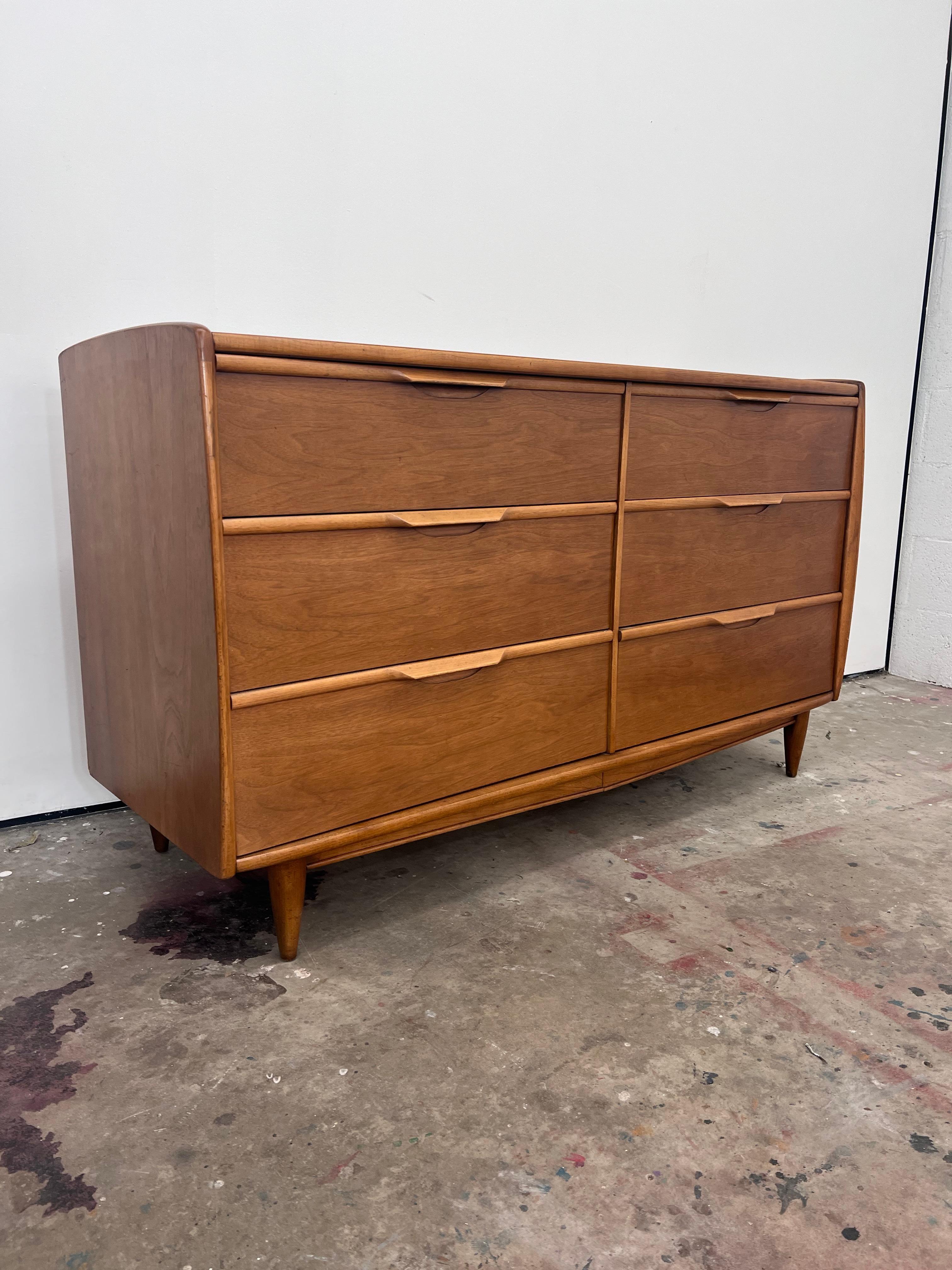 Petit 1960s Kent Coffey walnut 6 drawer dresser from their  “The Cadence” line. 

The original mirror is also Included. 

Dresser: 
54” long 
20” deep 
31.75” H 

Mirror: 
40” long
30” tall
 2” deep 
 Drawers feature sleek sculpted pulls. The piece