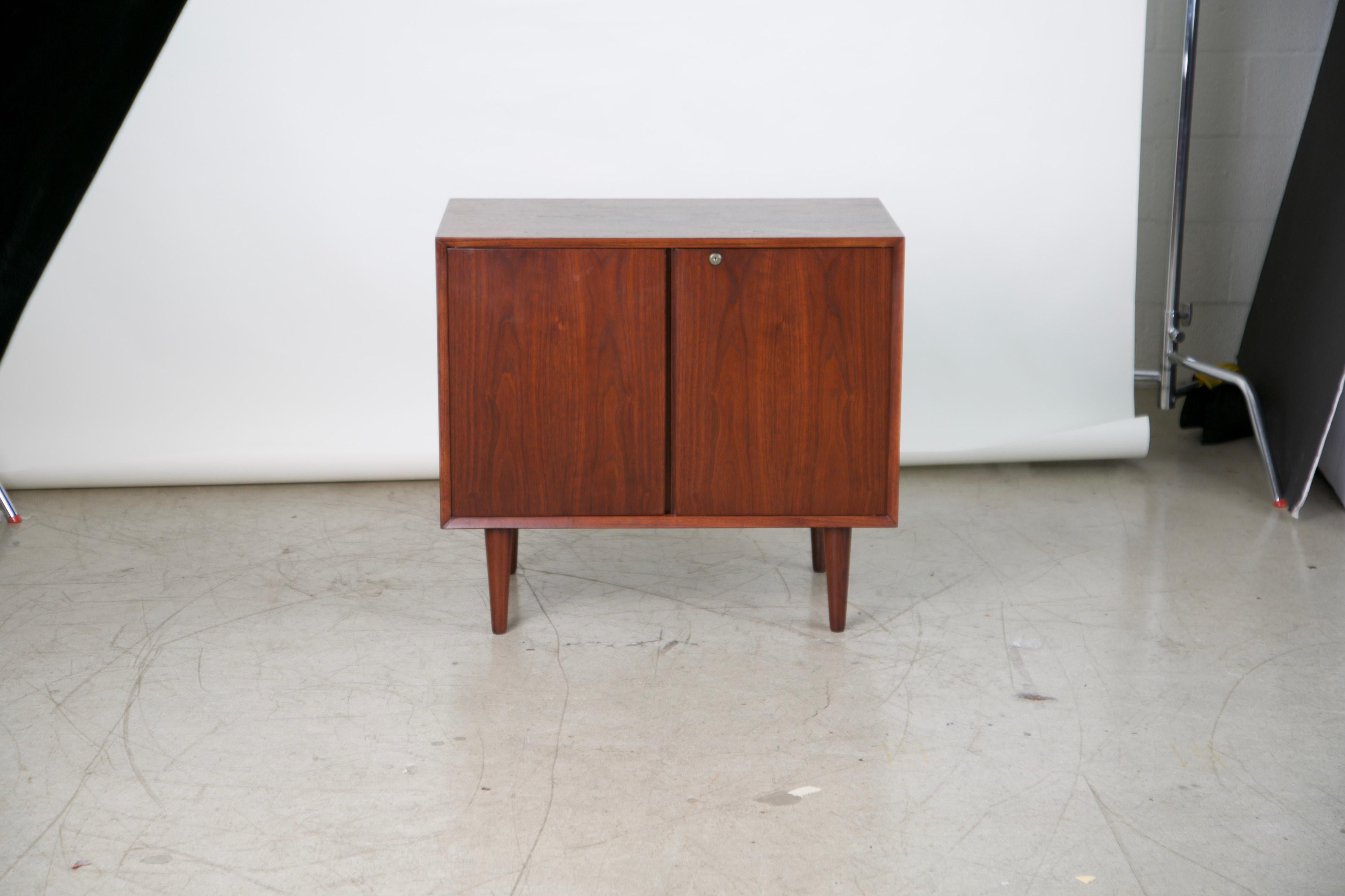 An adorable yet highly functional cabinet that can be locked to house your valuable or confidential items. This Mid-Century Modern cabinet has a beautiful walnut grain and inside has a single shelf. 

Possibly from Denmark, as it resembles popular