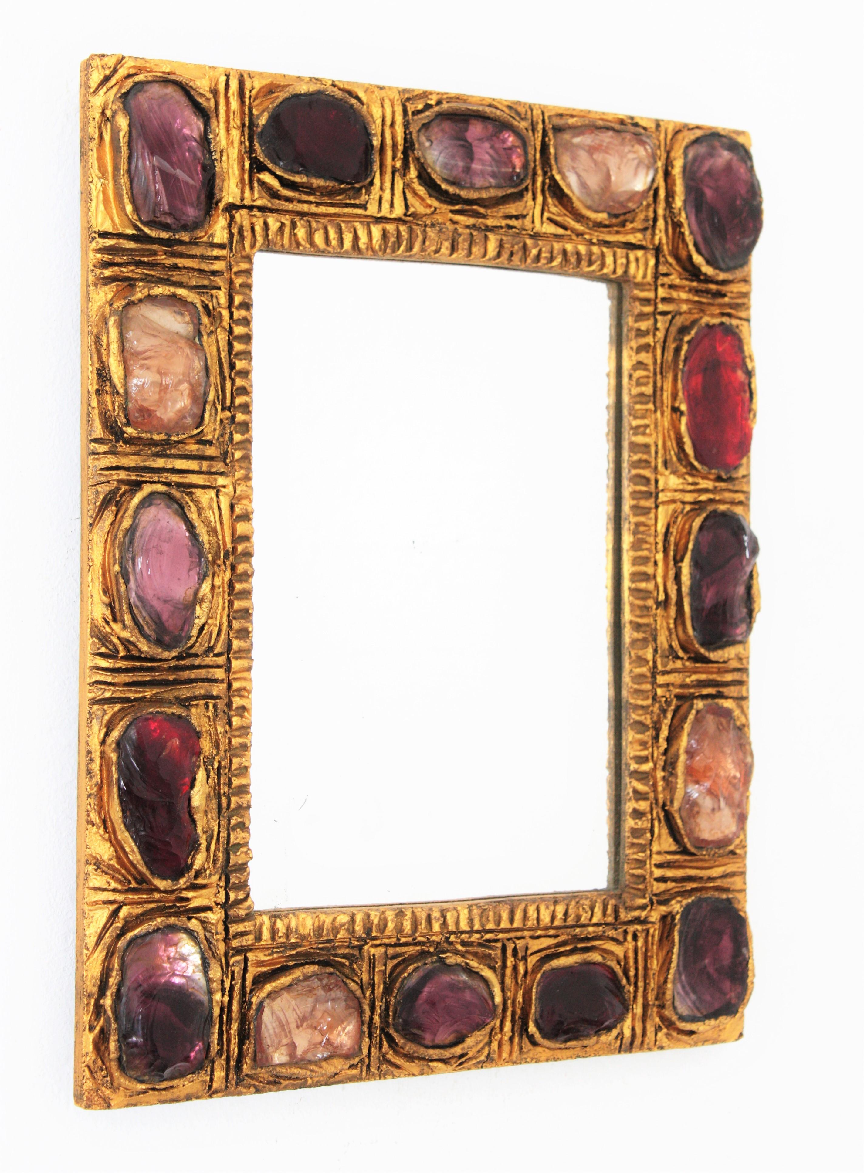 Rare Mid-20th century handcrafted rectangular mirror made of stucco with cased pink, purple and rubi red rock crystals on the frame. Beautiful frame made with pieces of colorful rock crystals and gold patinated finish. Lovely piece used as a vanity