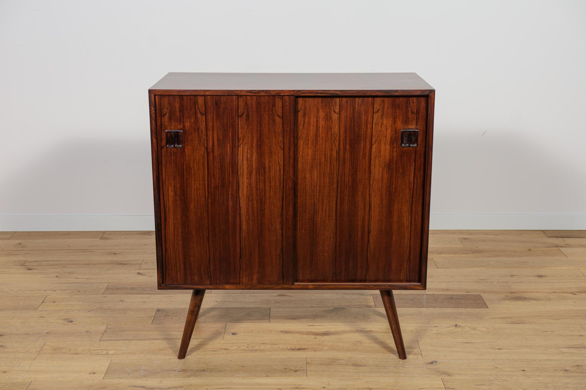 Un piccolo sidebord prodotto in Danimarca negli anni '60. All'interno della cassettiera c'è un ripiano. Credenza in palissandro. I mobili sono caratterizzati da un'interessante venatura dell'impiallacciatura e da maniglie e bordi profilati. Il legno