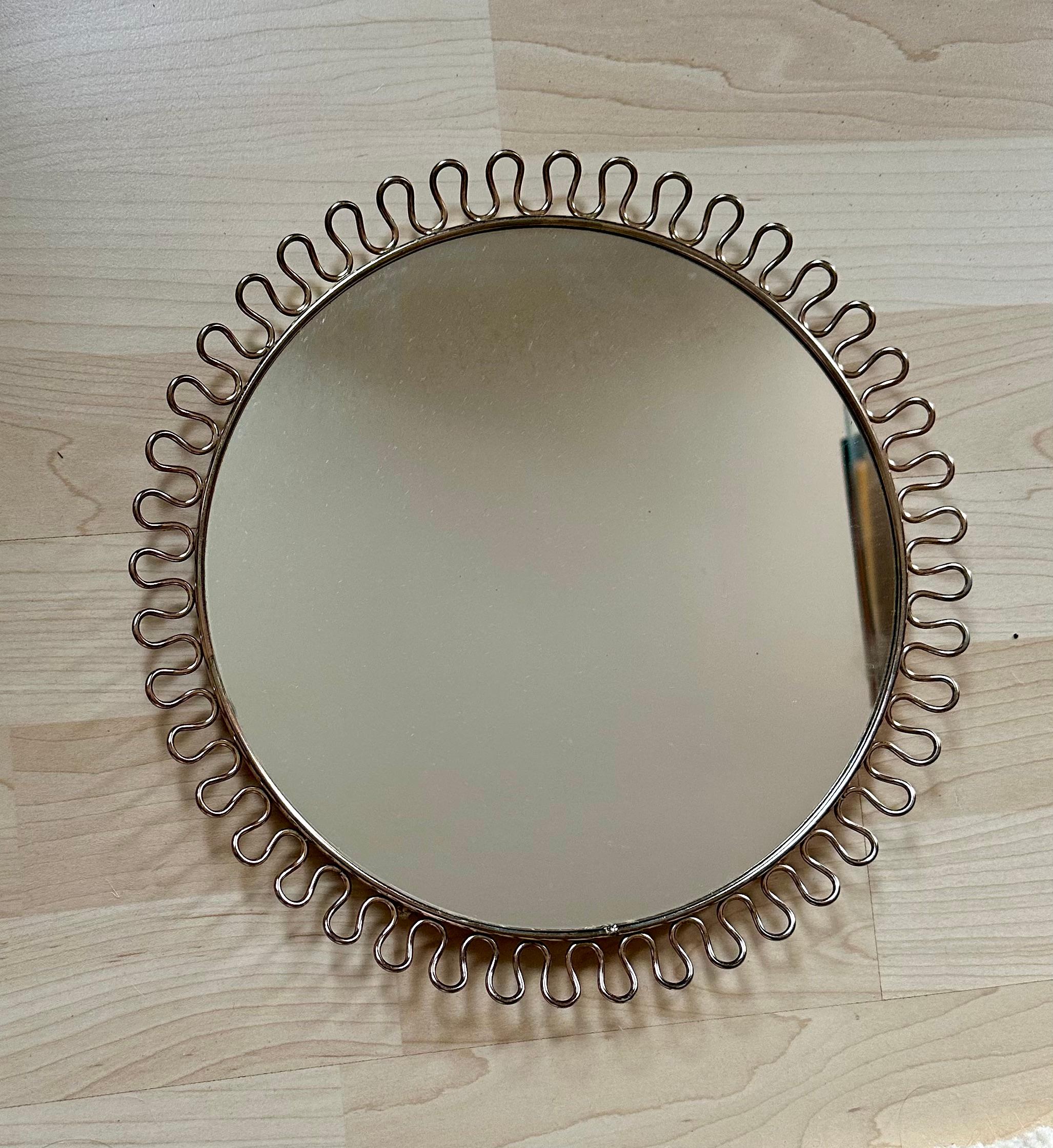 This small mid century mirror by Joseph Frank was designed and manufactured for Svenskt Tenn during the 1950s.
It is made of brass and has an original cord for hanging.
 Josef Frank was born in Austria in 1885. He was an architect, a designer,