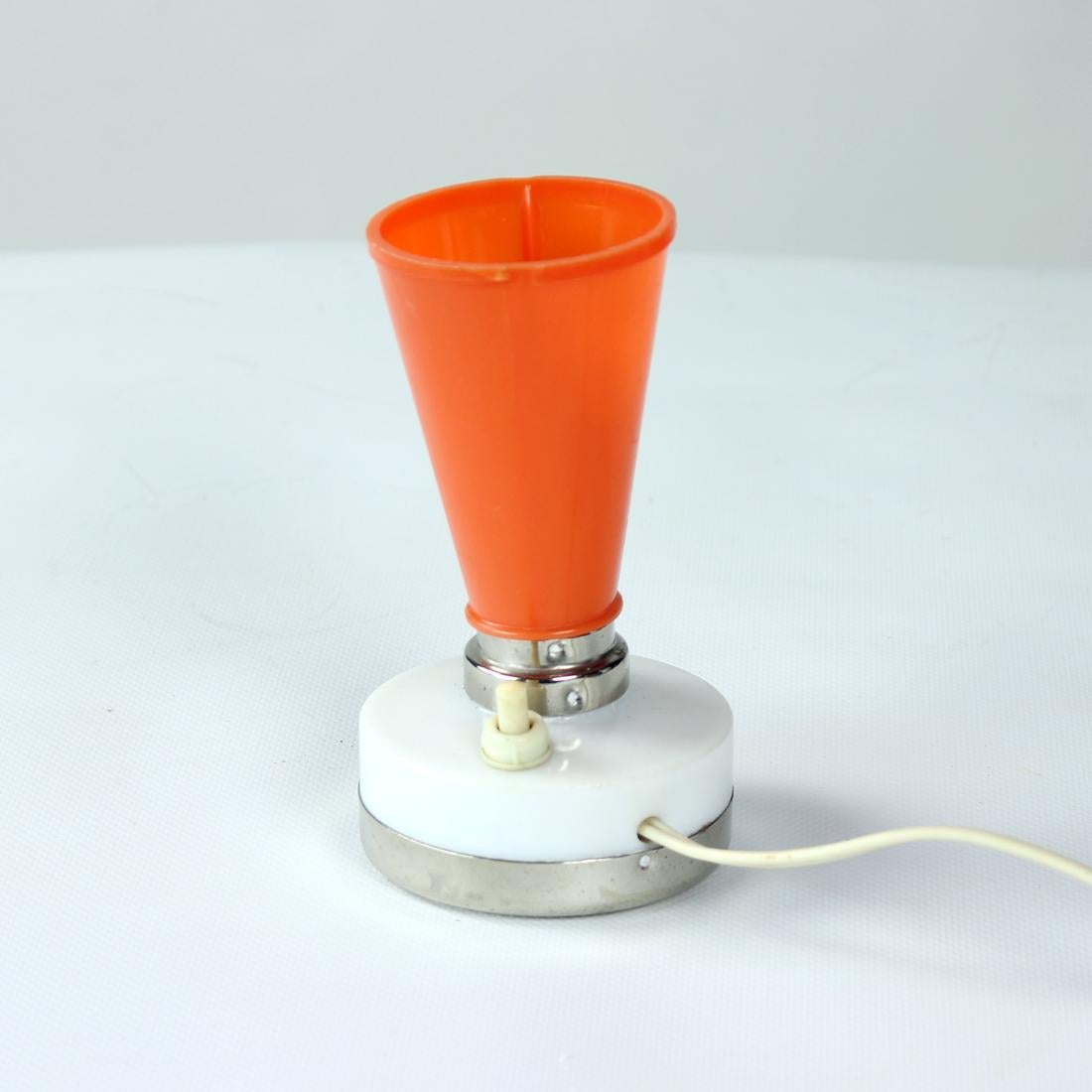 Beautiful, small table lamp, ideal for a mood light. Produced in Czechoslovakia in 1960s. The lamp combines the mid-century love with plastic and exciting design. The orange shield is made of plastic. The lamp works on one small bulb and is fully