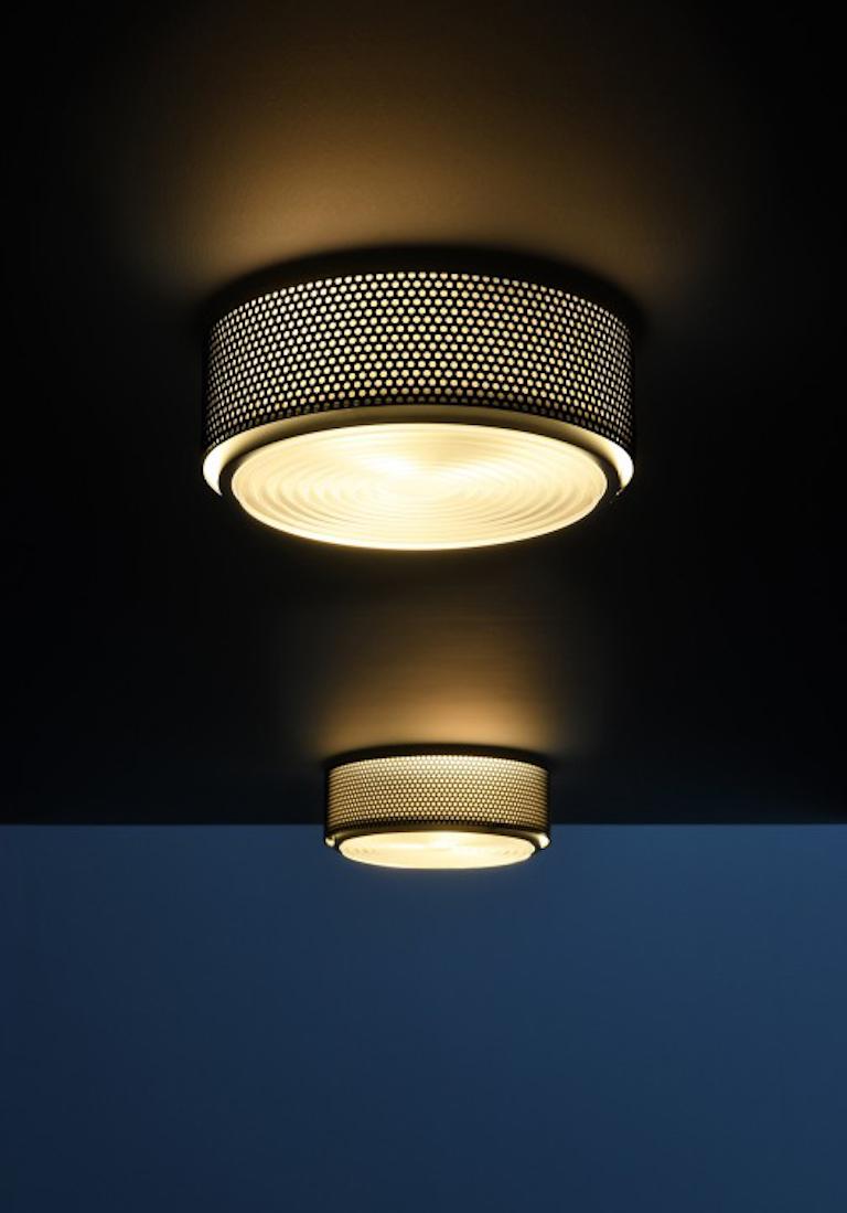 Small Model G13 flush mount wall/ceiling light by Pierre Guariche. Originally designed in 1952, this current edition is made in France by Sammode Studio. Black perforated metal base, authentic Fresnel glass lens. Wired for U.S. standards The G13 is
