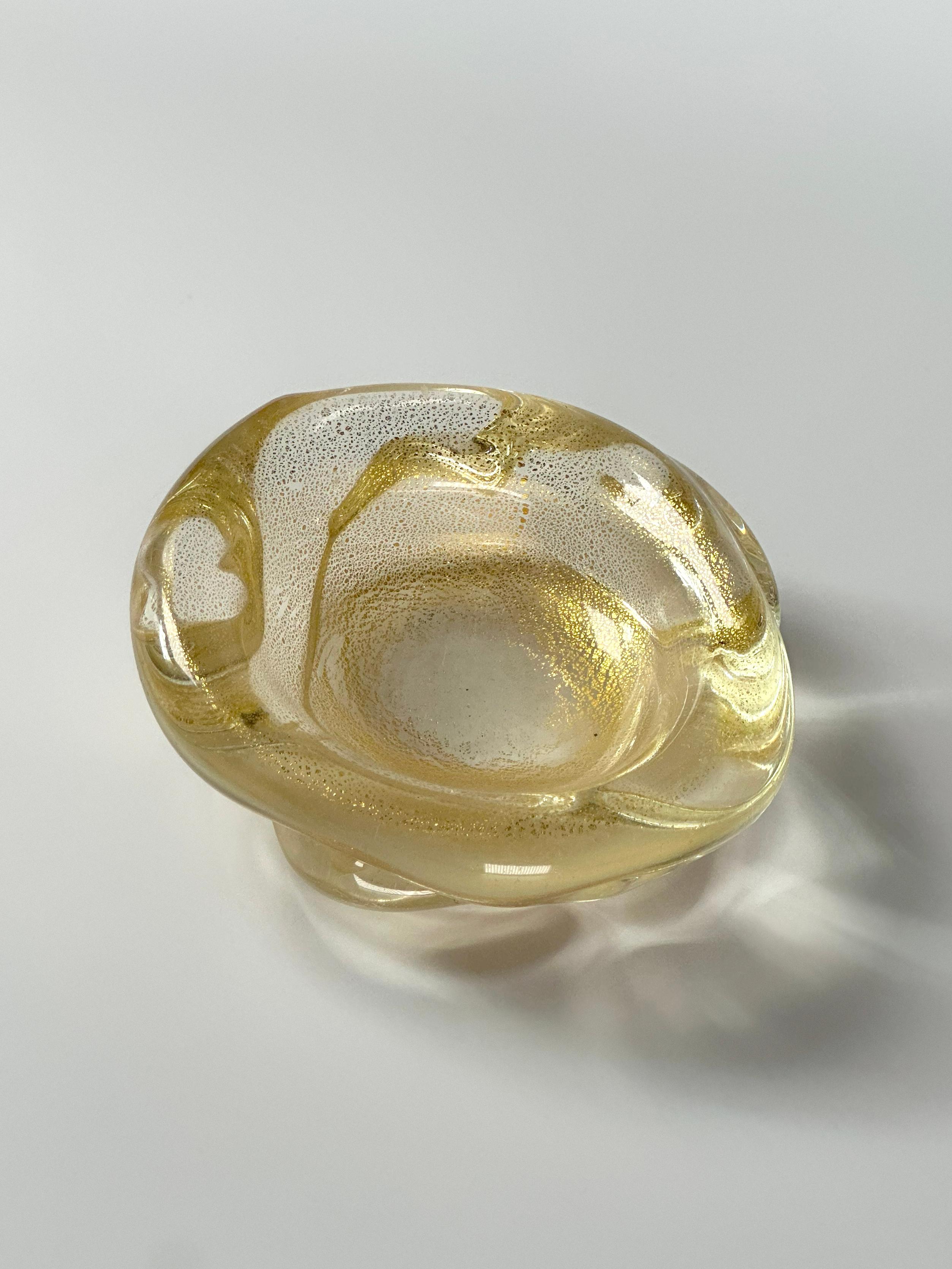 Ciotola decorativa in vetro di Murano a forma libera di Archimede Seguso, realizzata a mano in Italia negli anni Ottanta. La piccola ciotola è realizzata in vetro trasparente di Murano con inclusioni d'oro in sospensione. La fusione del vetro e