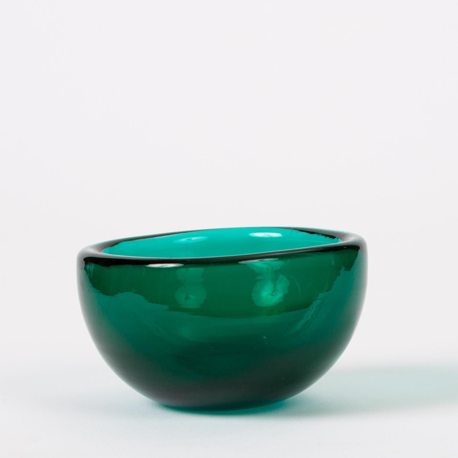 A small Murano glass dish by Venini, in a design commonly attributed to Carlo Scarpa, the company’s artistic director in the 1930s and early 1940s. This modest bowl has four slightly bowed sides and rounded corners. The deep teal blue glass is