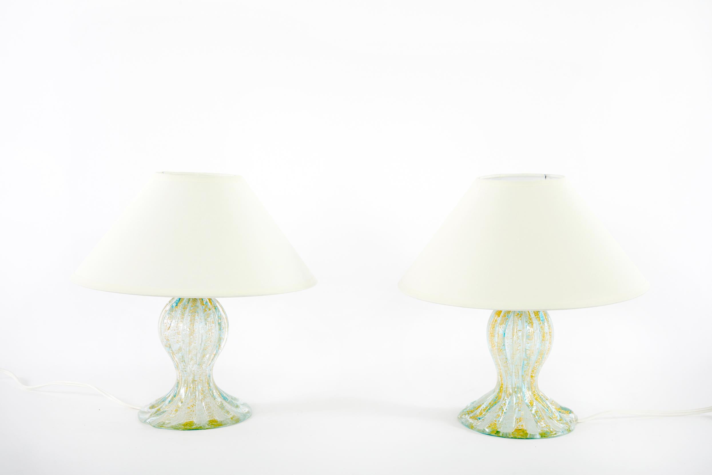 Very small late 20th century Murano glass with gold flecks design details pair table lamp with round bell shape linen exterior shade . Each lamp is in excellent working condition. Rewired for US use. From base to finial each lamp stands about 12