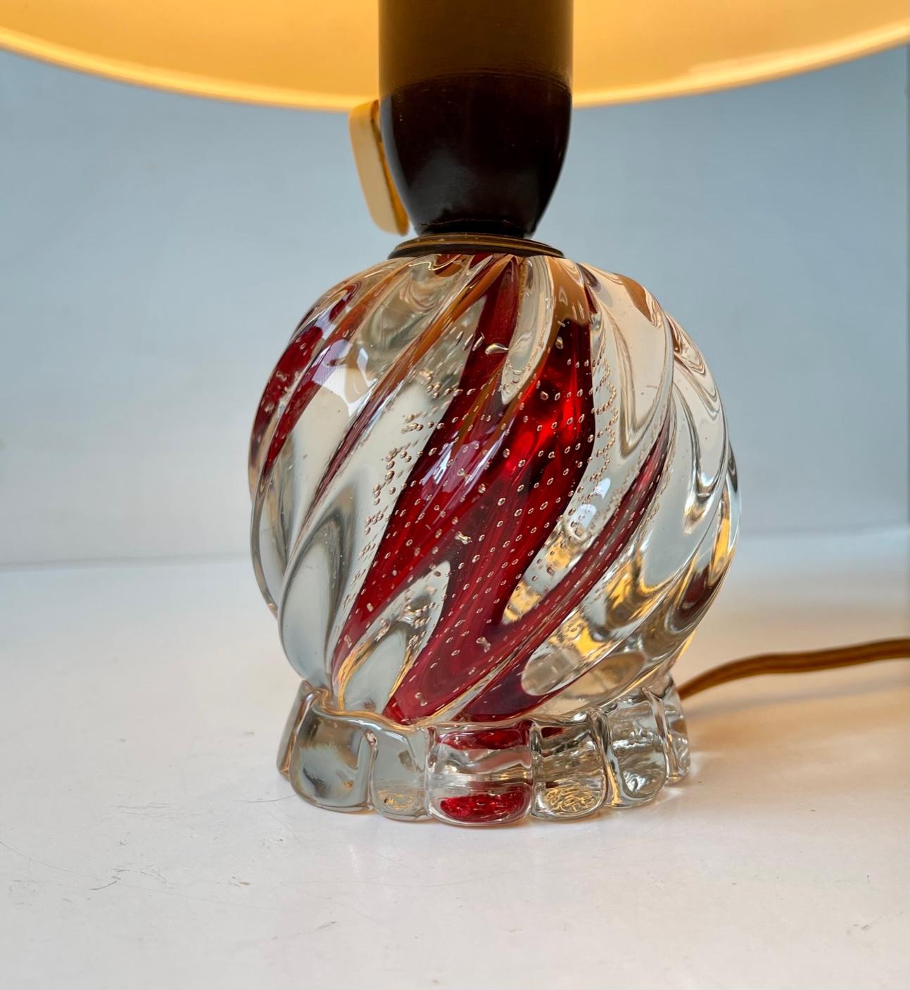 Small fluted table lamp in red and clear hand-blown glass with internal air bubbles. Made in Murano Italy during the 1950s probably by Seguso. It features a off-white textile shade and a bulit-in on/of switch to its original bakelite socket.
