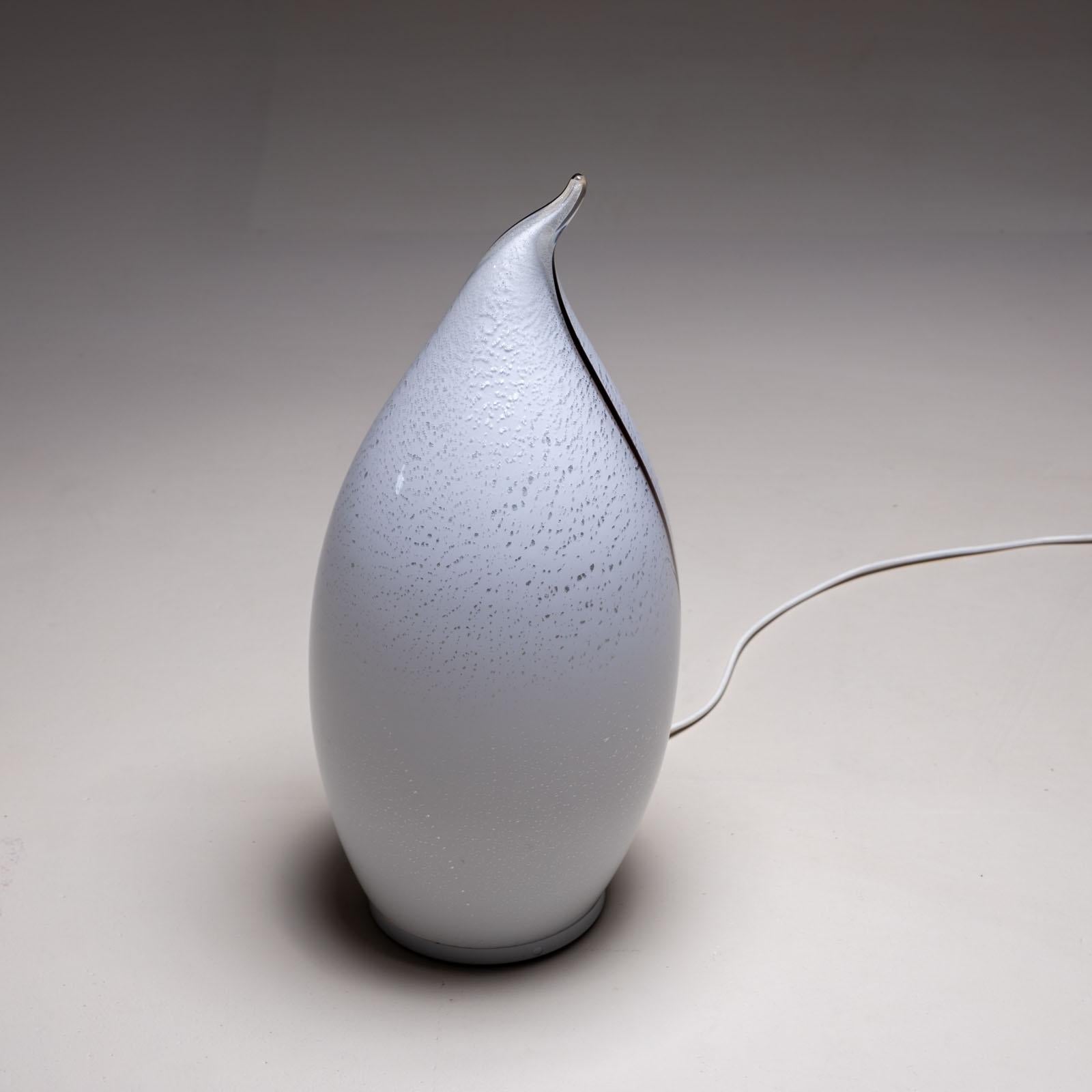 Pequeña lámpara de mesa de cristal de Murano con un cuerpo blanco en forma de gota con inclusiones de burbujas de aire y una línea negra. 