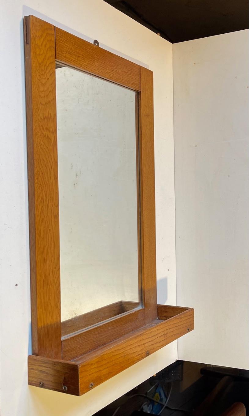 A small and plain wall mirror with underlying shelf for your bathroom smalls. It is made from oak. It has been used on a Danish navy ship in the chefs cabin at the stern. So it says to its backside in Danish. It all makes sense since the raised