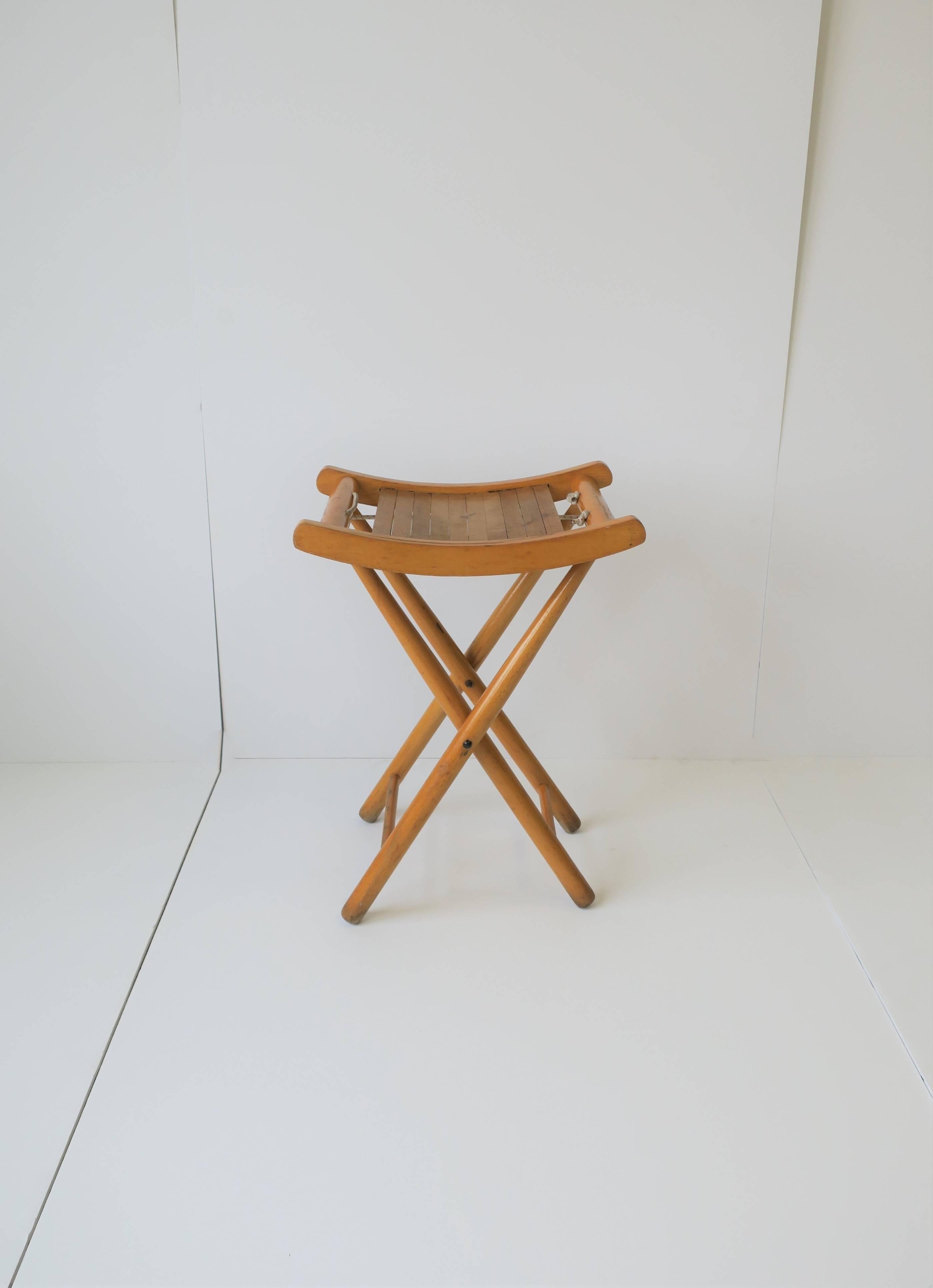 A small vintage blonde wood folding stool or bench with nautical rope detail. Piece can also be used as a side table providing there is a book on top as a stable environment for a glass, etc., (see images #6 and #8 showing book with sea shell.)