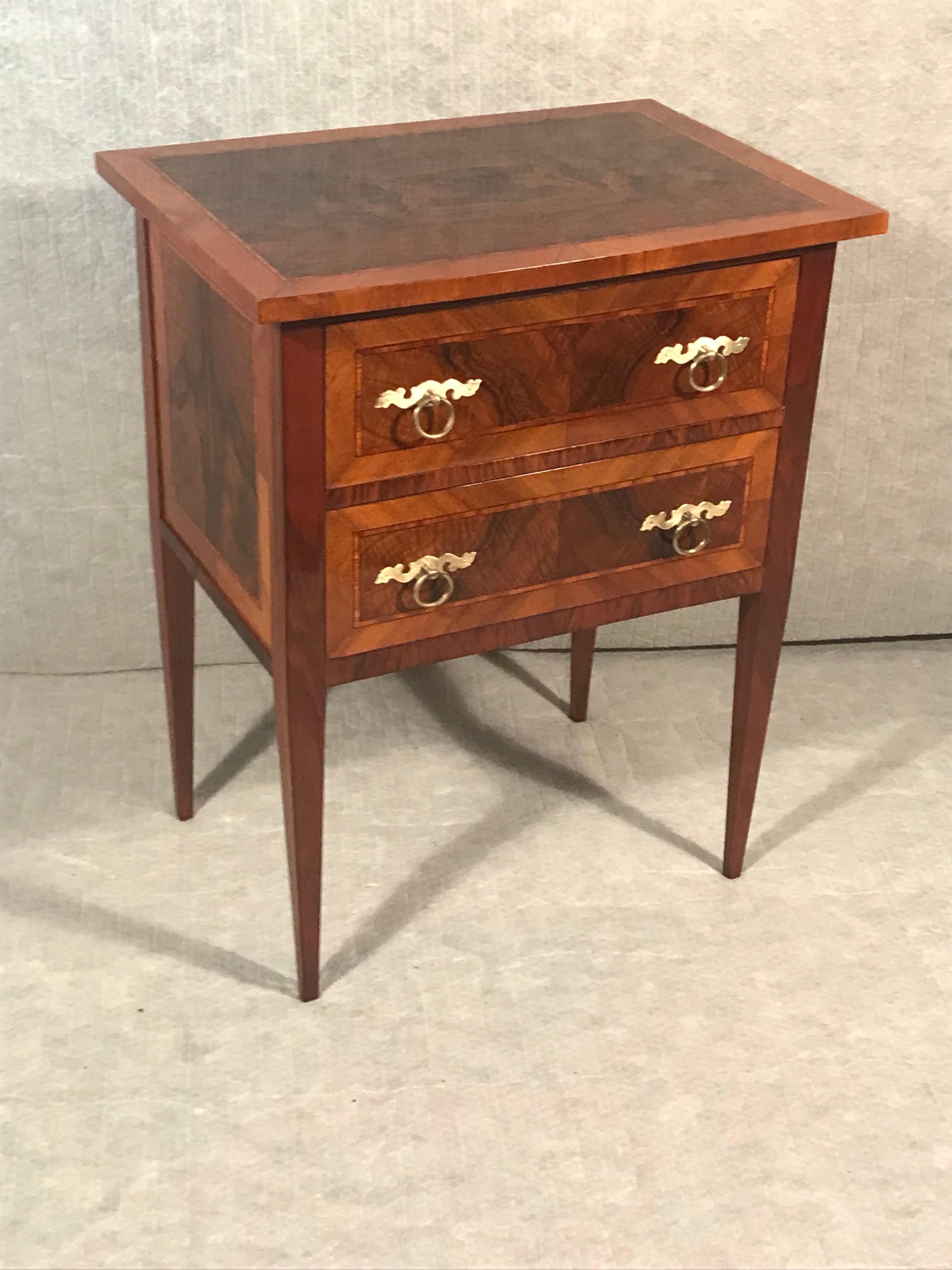 Discover the timeless elegance of this meticulously crafted 19th-century German Neoclassical chest of drawers or nightstand. Adorned with captivating walnut veneer grain, this piece exudes charm and sophistication. Standing gracefully on slender