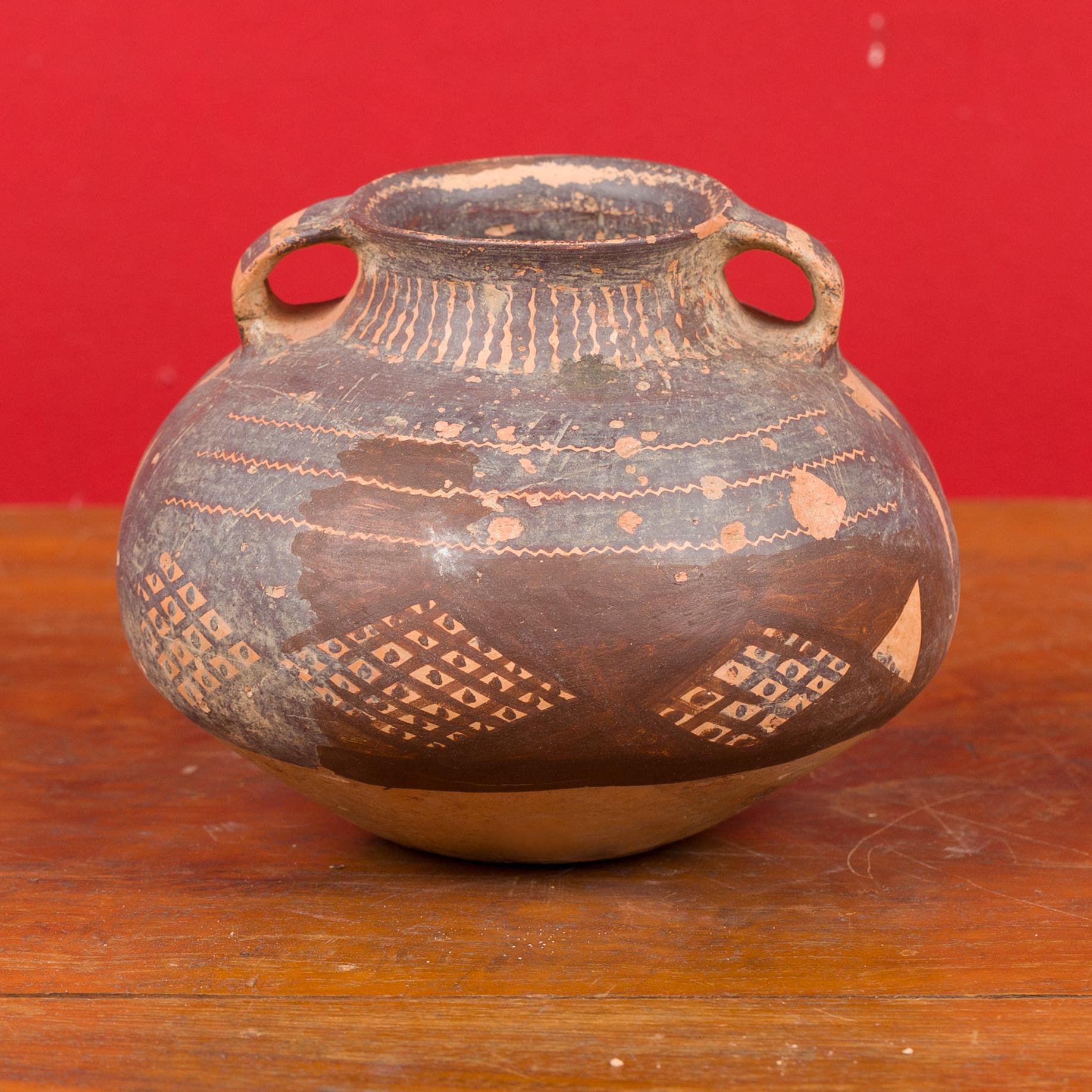 A Chinese Neolithic terracotta pottery from 4000-3000 BC, with lateral handles and brown painted geometric décor. Born in China during the Neolithic period, this pitcher attracts our attention with its nice patina, simple lines and geometric motifs.