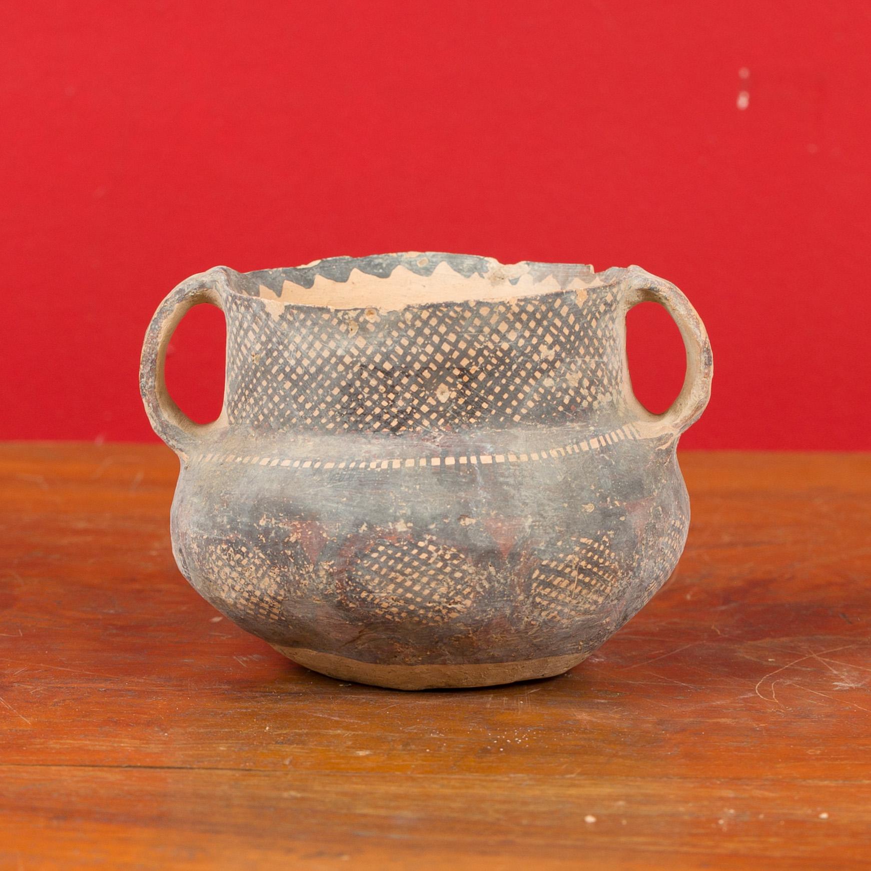 A Chinese Neolithic terracotta pottery from 4000-3000 BC, with lateral handles and black painted geometric decor. Born in China during the Neolithic period, this pitcher attracts our attention with its nicely weathered appearance, simple lines and