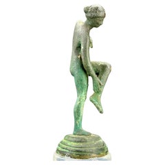 Petite sculpture de femme nue posant sur une base en lucite