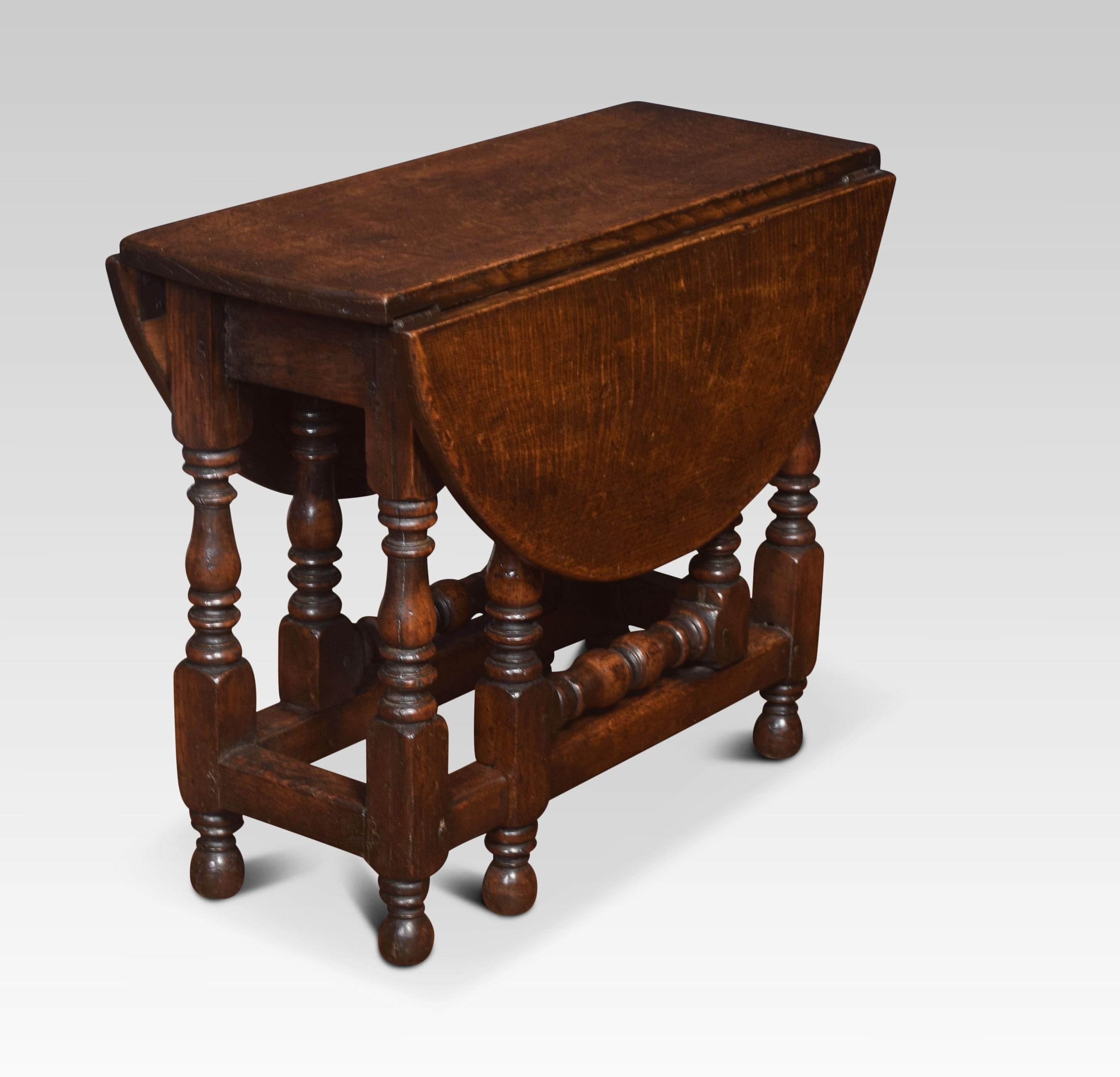 Solid oak gateleg table, having an oval drop-leaf top raised up on turned supports united by stretchers.
Dimensions:
Height 19 inches
Width 10.5 inches when open 27 inches
Depth 24 inches.