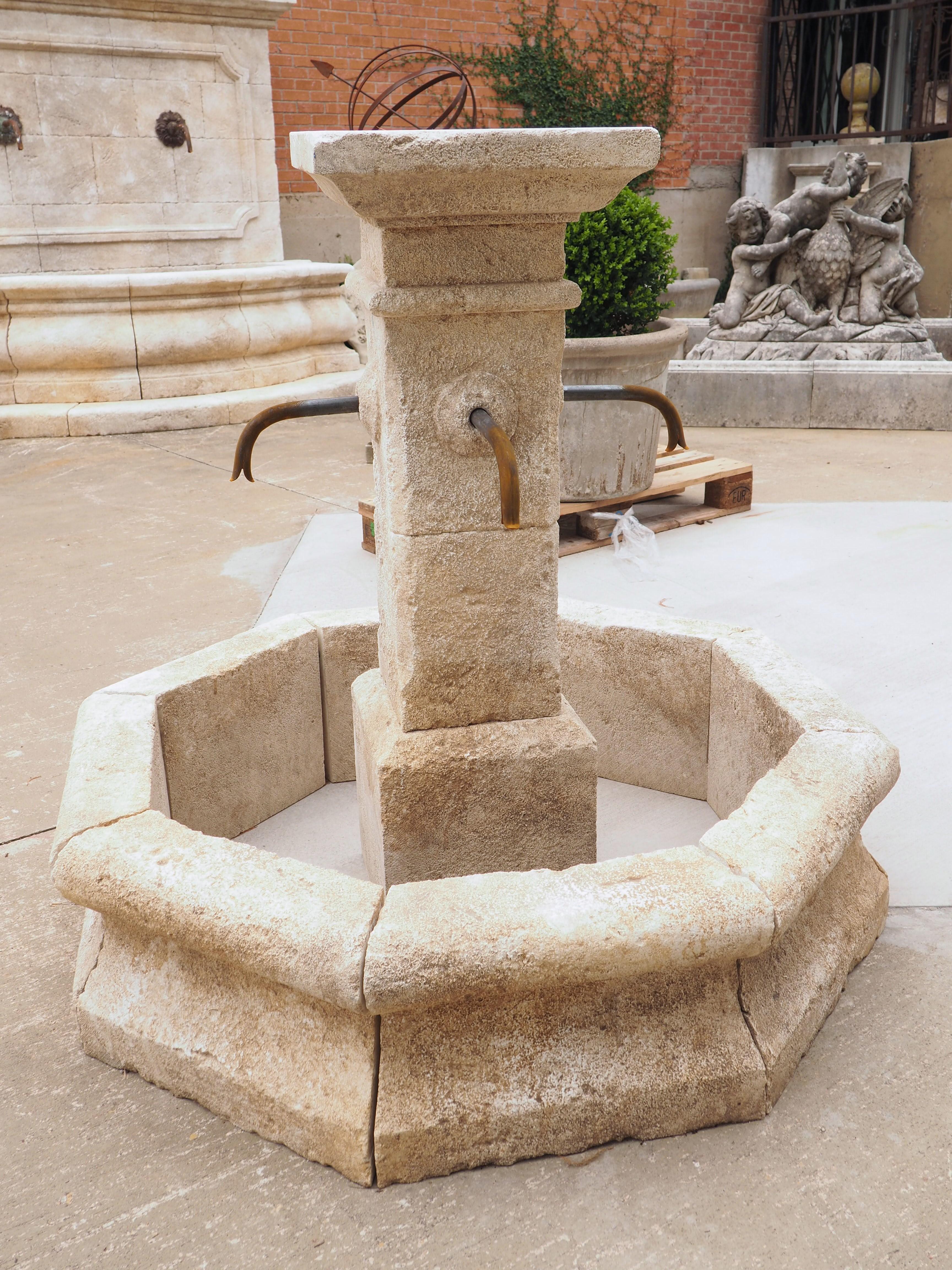 This small center fountain was hand-carved in Provence, in the South of France. Comprised of 13 pieces of stone, the fountain features an octagonal basin with a rectilinear column. Each of the eight basin wall stones have been carved with a large