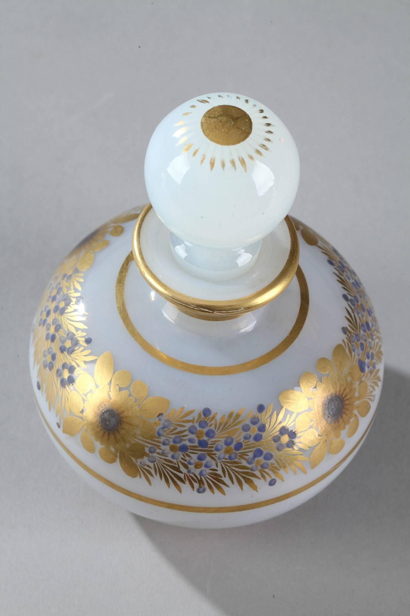 White bulle de savon (soap bubble) opaline perfume bottle with its ball-shaped stopper topped with petals. Gilded stripes decorate the neck and a blue wreath of anemones and forget-me-nots adorn the paunch. This exquisite decoration was produced by