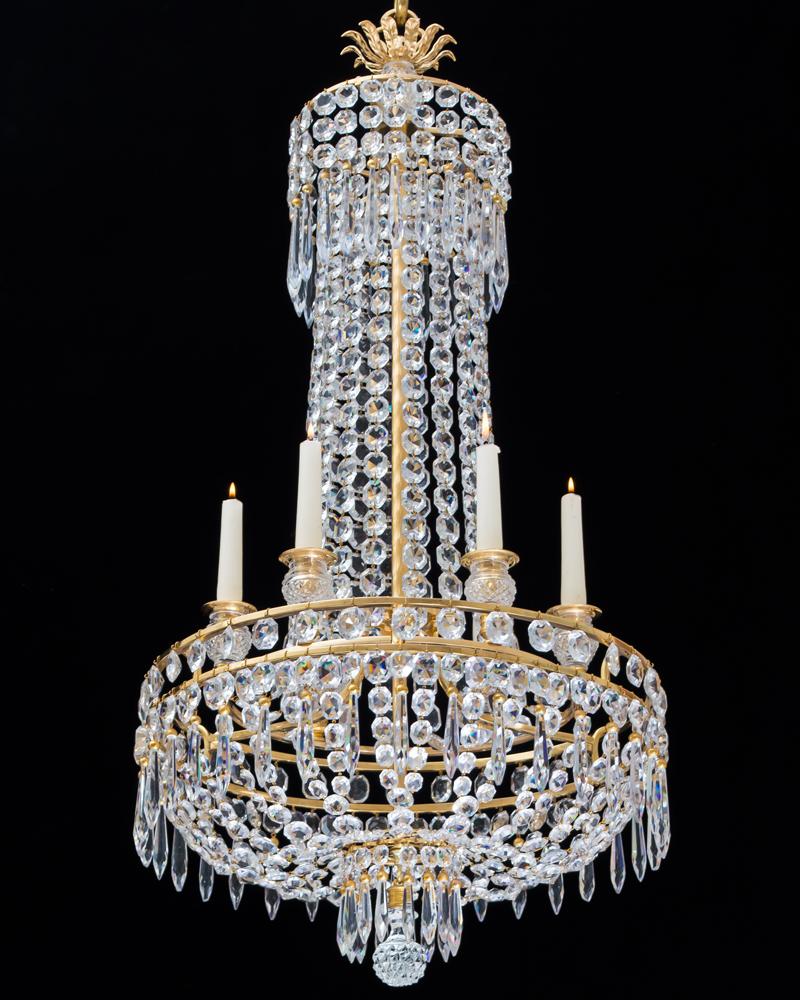 A fine Regency chandelier of tent and basket design with double ormolu bands issuing six diamond cut glass candle nozzles, the chandelier is hung with double cut rectangular spangles and ormolu-mounted caped icicle drops terminating with diamond cut
