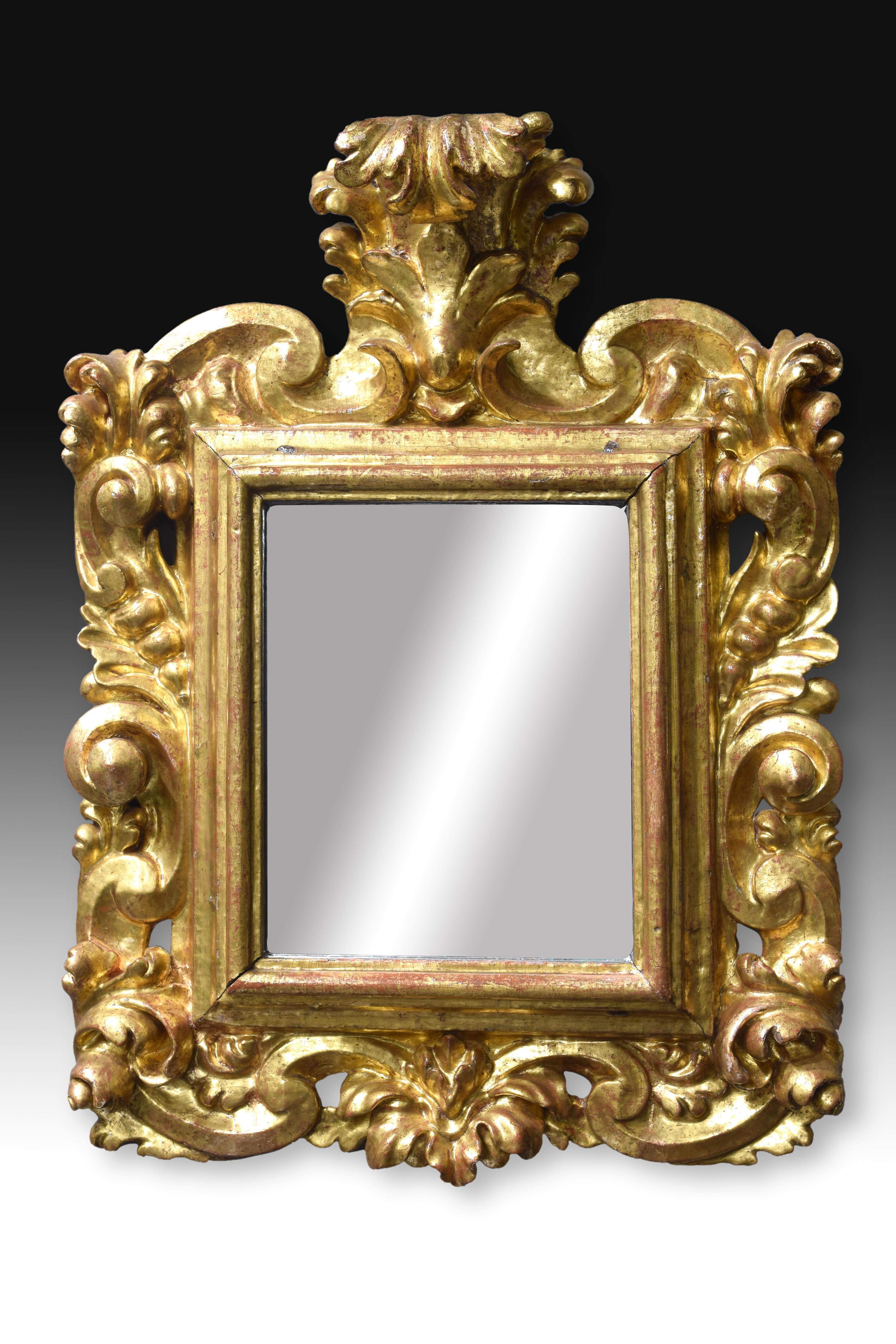 The fleshy decoration of the exterior of this mirror, and its movement, places this artpiece in the Baroque, but both the harmony and the symmetry and the fact that the decoration does not just protrude from the rectangular frame (except for the