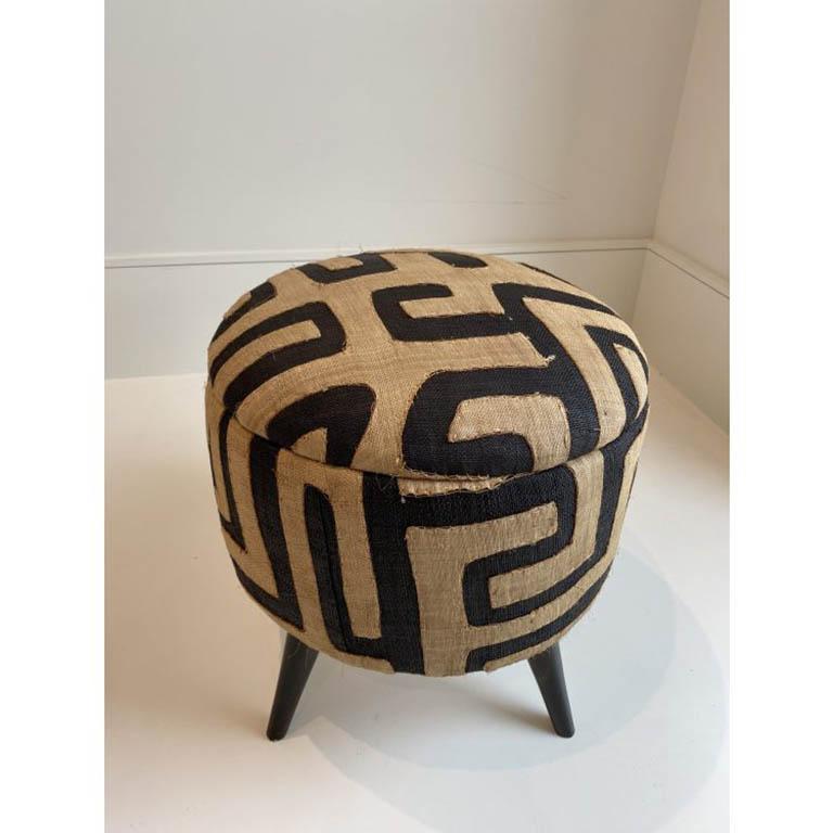 Small ottoman dressed in dimensional Kuba cloth material.