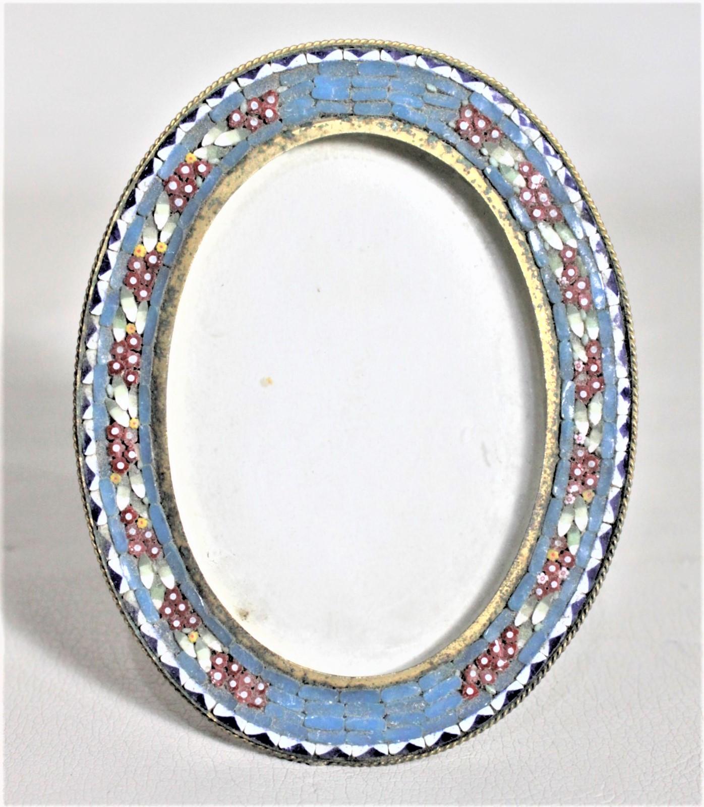 This small oval art glass and brass picture frame is unsigned, but presumed to have been made in Italy in approximately 1920. The frame is composed of a brass frame with art glass caning on the front done with a green and white geometric border and
