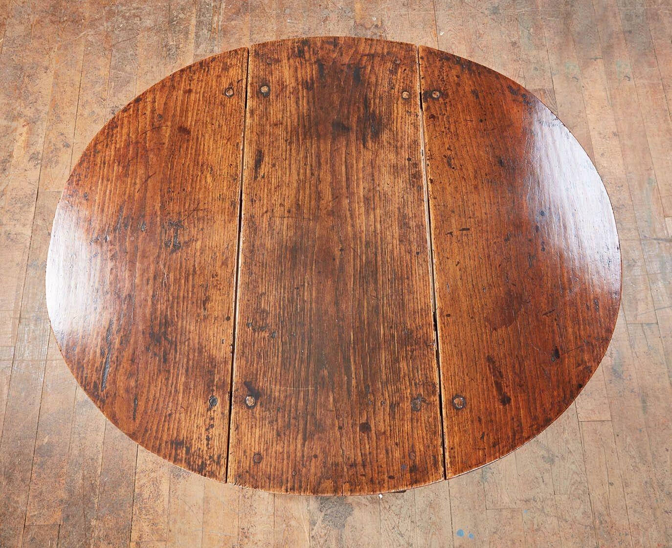 Ein kleiner Tisch aus englischem Eichenholz mit traditionellen Klappen, die auf zwei Toren ruhen, die sich zu einem Korpus mit charakteristischen Kanonenbeinen zusammenklappen lassen, die durch doppelt gedrehte Bahren verbunden sind. Gedübelte