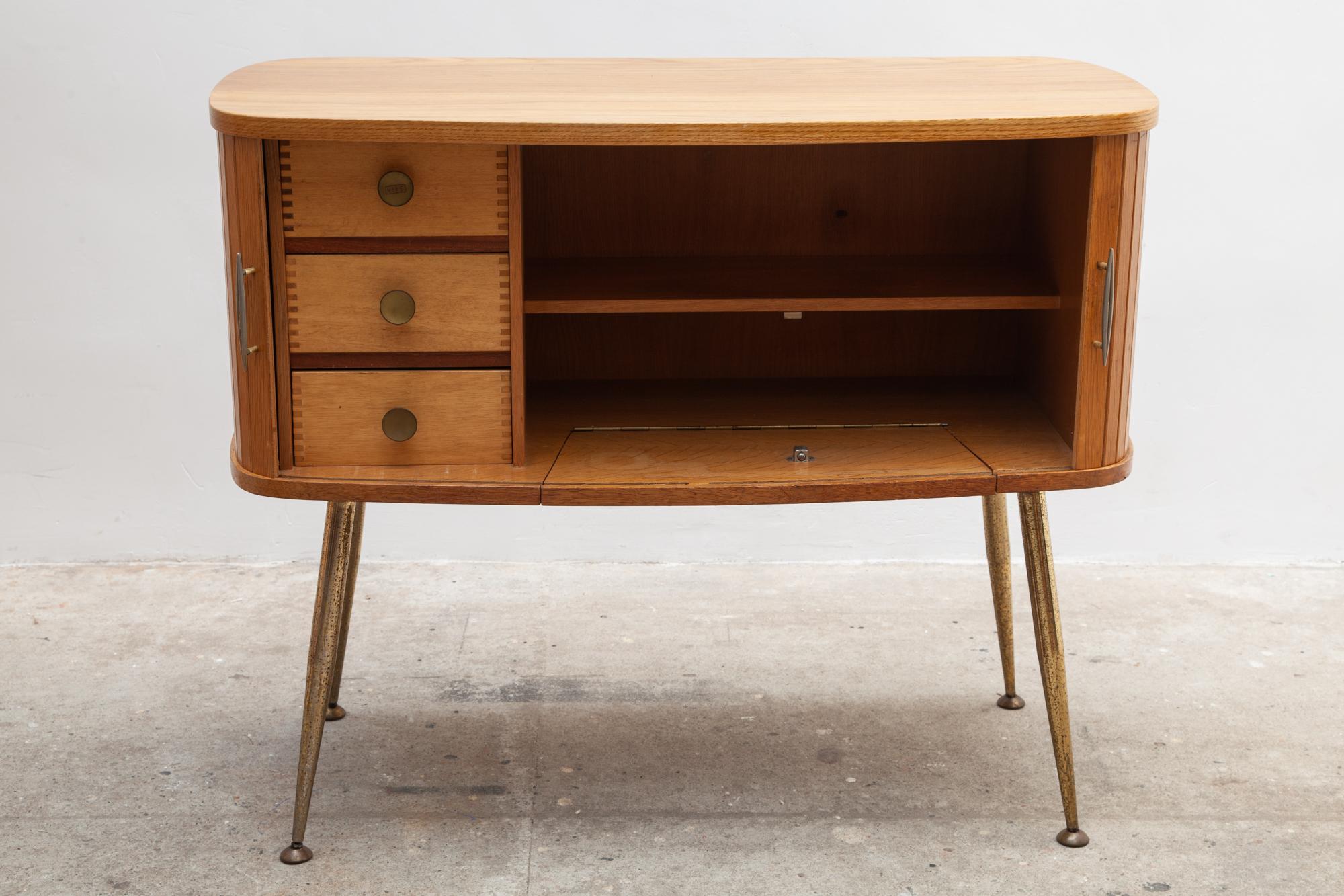 Beautiful shop display sideboard or desk with two sliding doors in oak in an oval design. If you open the sliding doors with two brass handles, a flap will appear that you can open up so that there is free space to sit at and can be used manually as