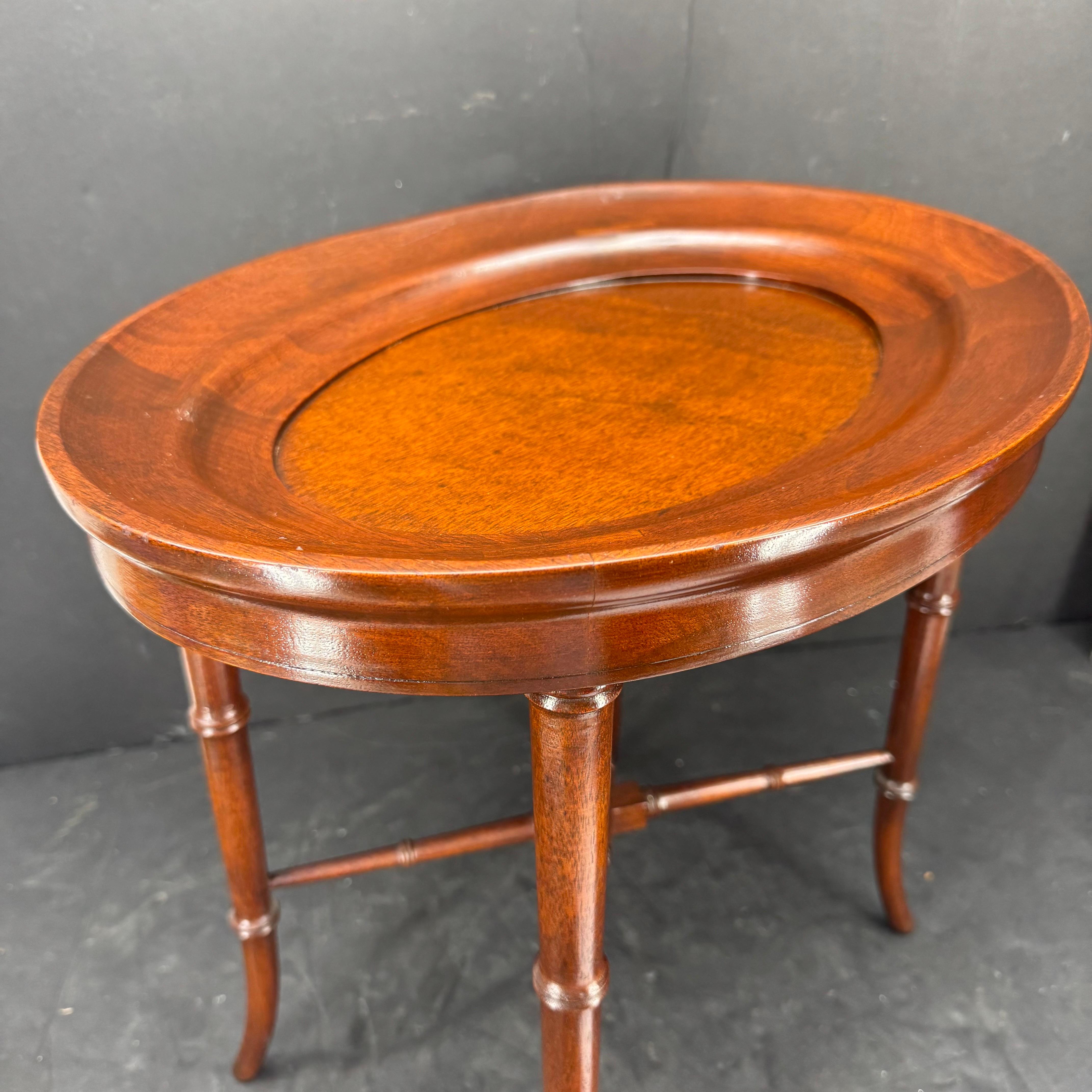 Charmante table d'appoint ovale en bois avec pieds en faux bambou. Cette table de style classique serait parfaite à côté d'une chaise dans un salon formel ou informel ou dans une bibliothèque. 
