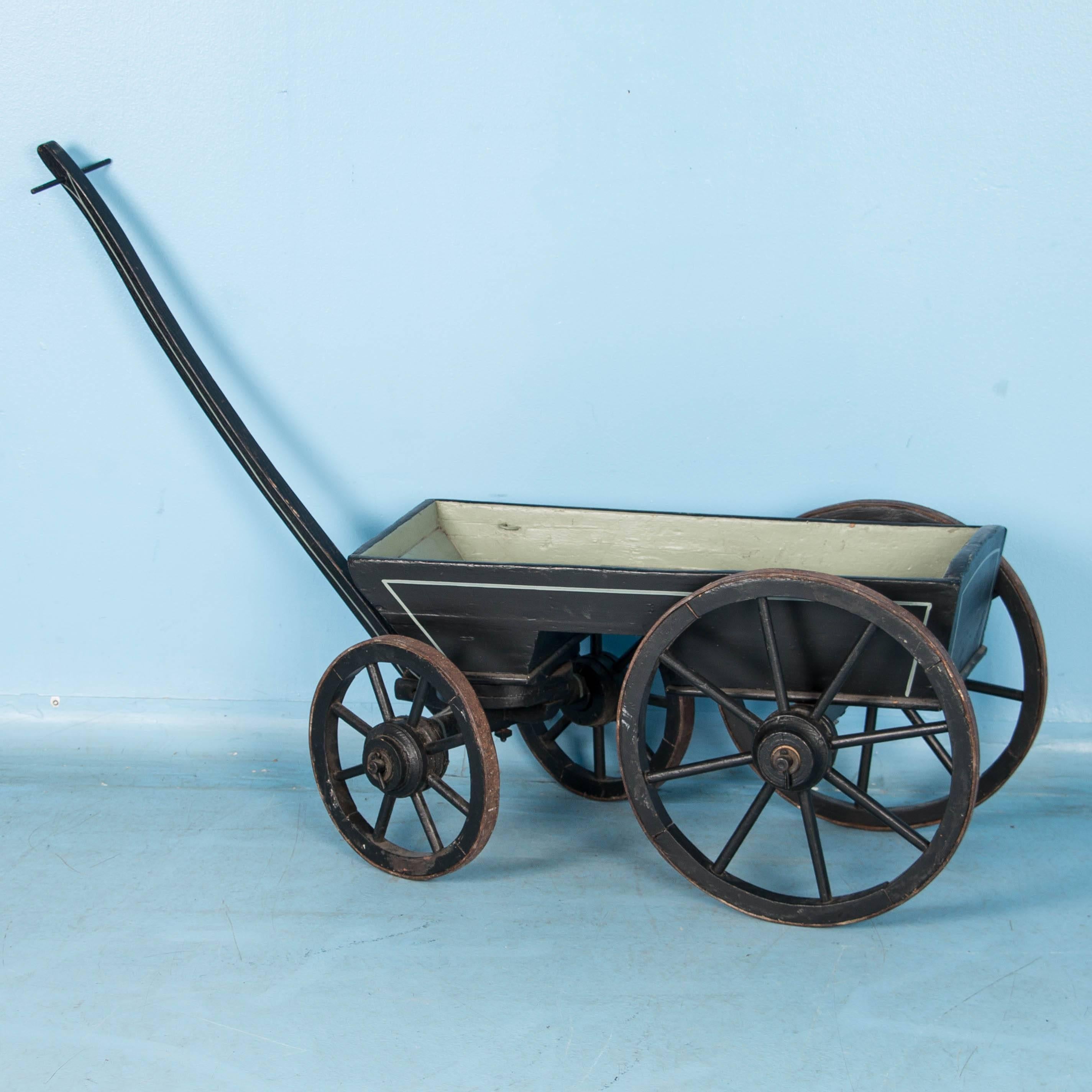 This late 19th century farm style wagon has a wonderful aged patina with the exterior painted black and a sage green interior.  Different than most farm wagons, this one was probably made for children, with it's solid sides and interior seat. The