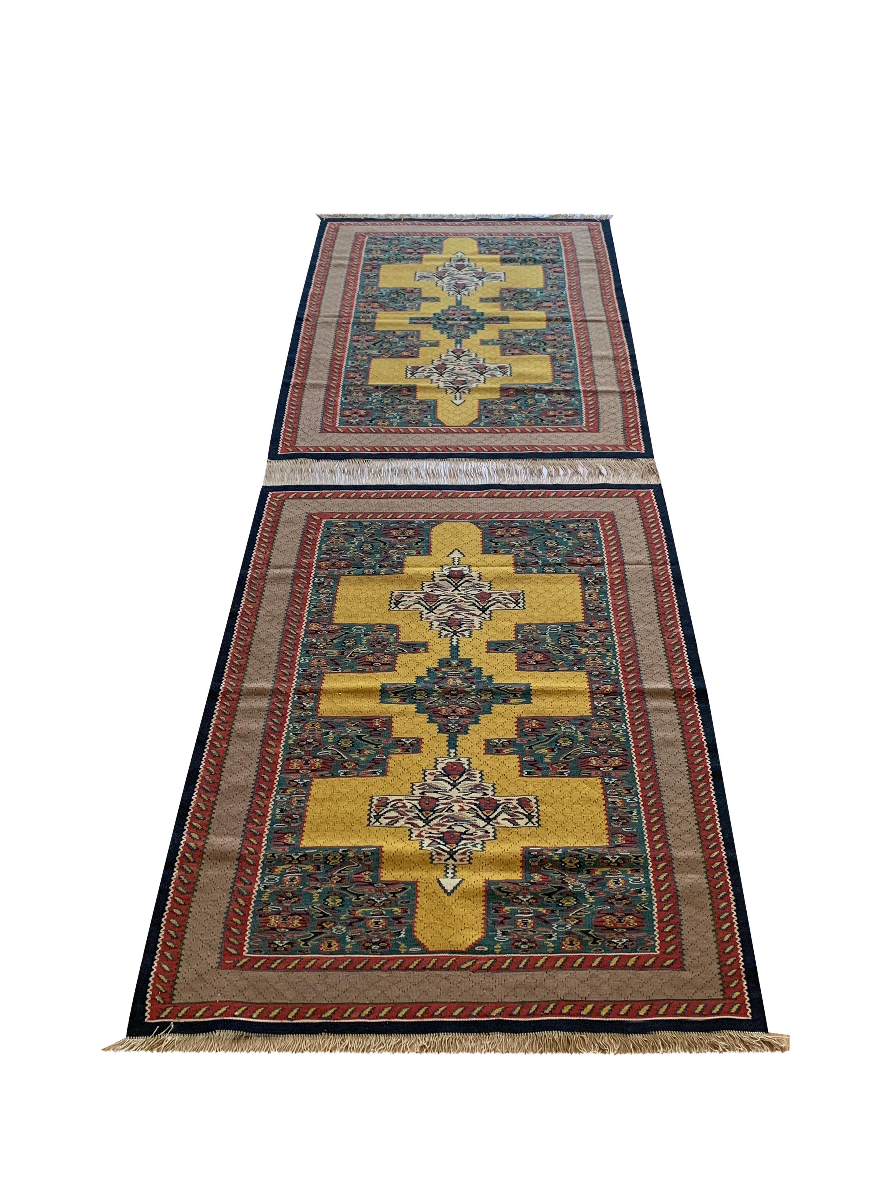These bold wool rugs are a matching pair of handmade flatwoven kilims, woven by hand in the early 2000s, circa 2010. The design features a trio of geometric medallions woven in accents of ivory, green and red on a yellow background. This has then