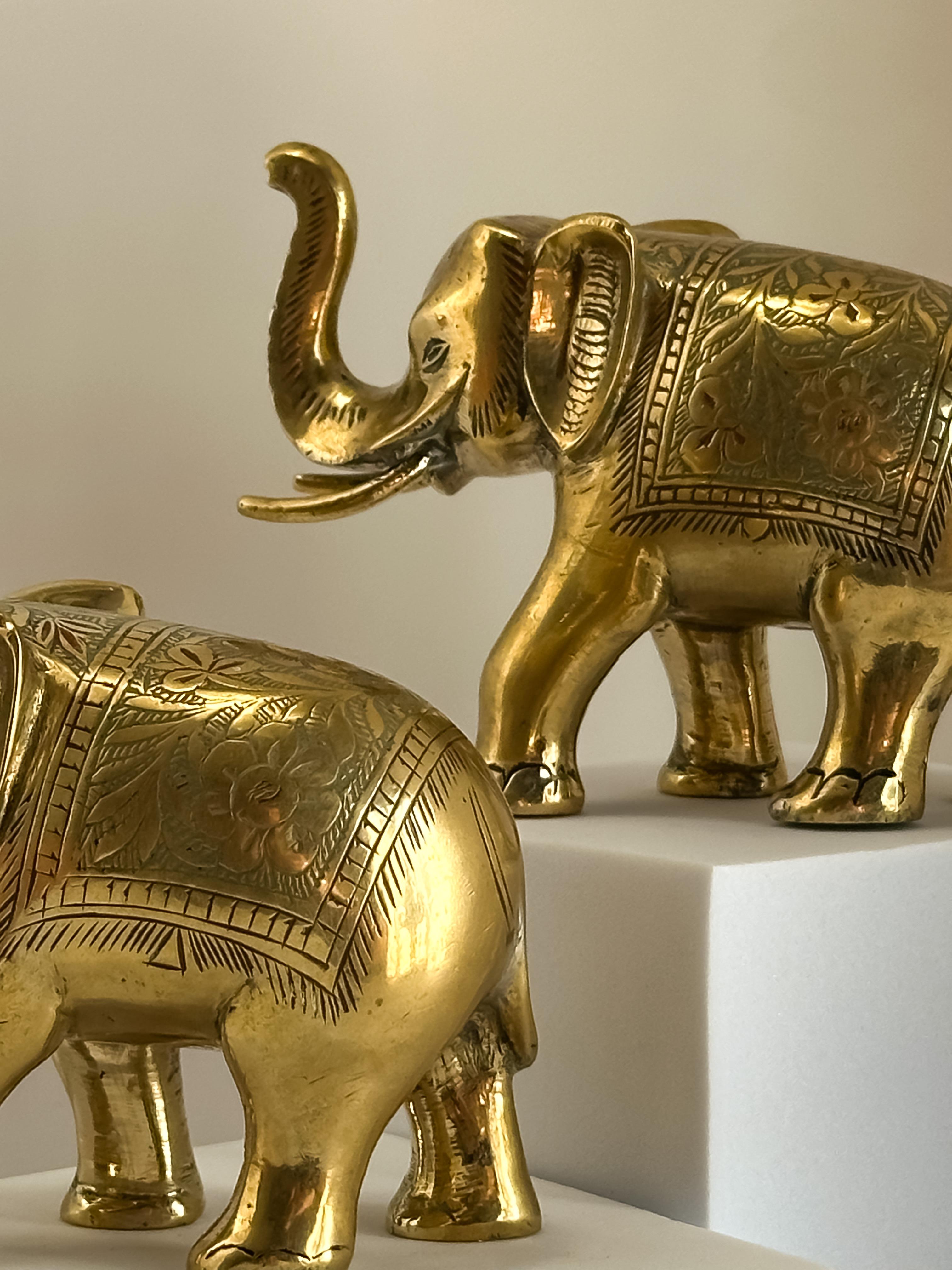 A small pair of enamelled brass Anglo-Indian elephant ornaments crafted in India in the 1960s. 

Each elephant is decorated with fine Indian-style motifs filled with glass enamel in subtle verdigris and red tones. The brass has been cast; perhaps