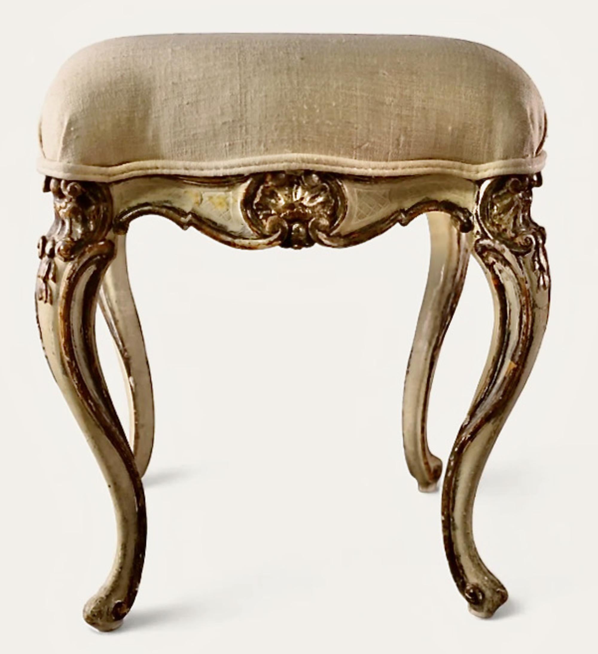 This is a charming petit vanity stool that dates to the late 19th or early 20th century. The stool is finely carved in a shell motifs to side and tops of exagerated cabriole legs. The stool is further paint and gold leaf decorated.
The stool makes