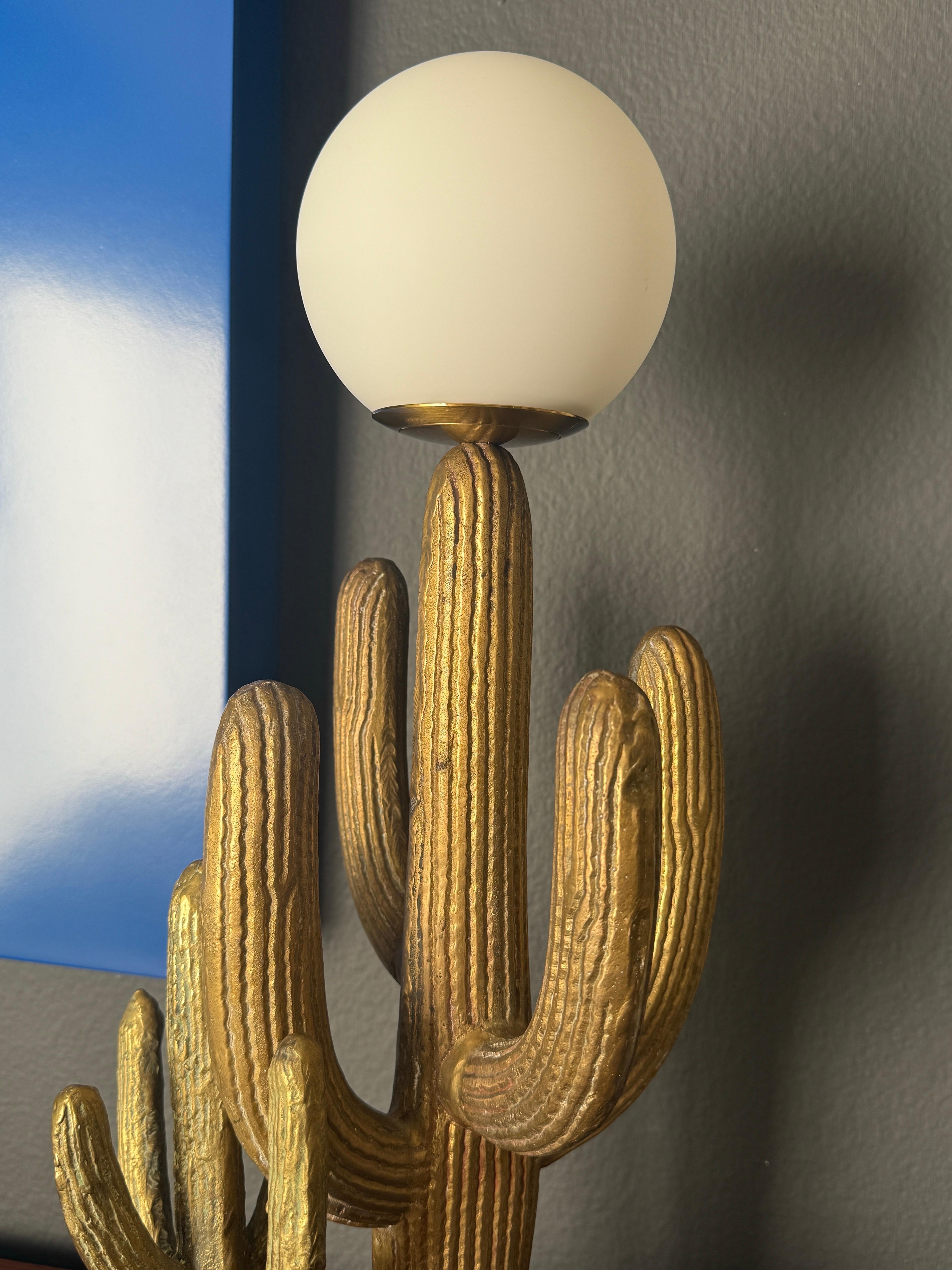 Pequeña lámpara de latón patinado con cactus saguaro montada sobre base de madera negra. El globo tiene un diámetro de 4,5