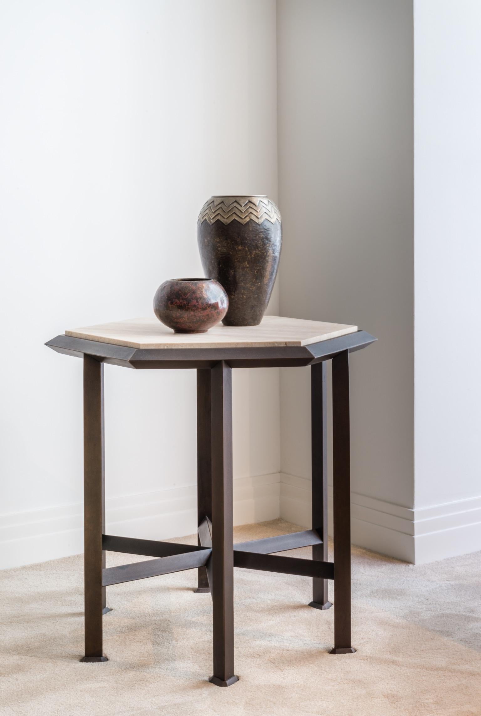 Patinated bronze and softened travertine.

Limited edition of twelve numbered and signed pieces.
The Orion pedestal table is a real gem of geometry. All its constituent elements are based on the figure of the triangle. Its base is a clever